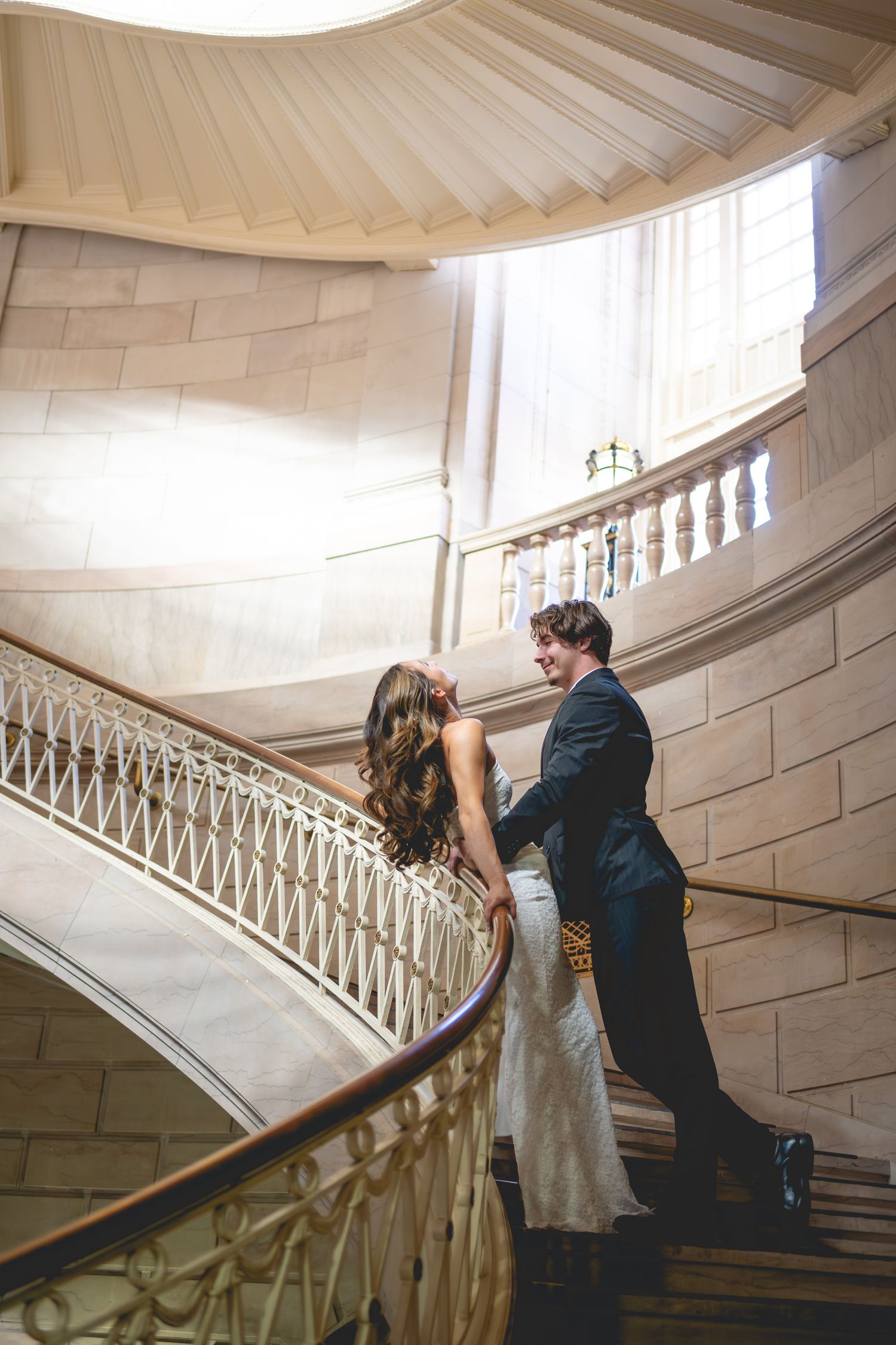 Romantic couple photos on curved marble staircase with ornate white railings at Hartford City Hall.