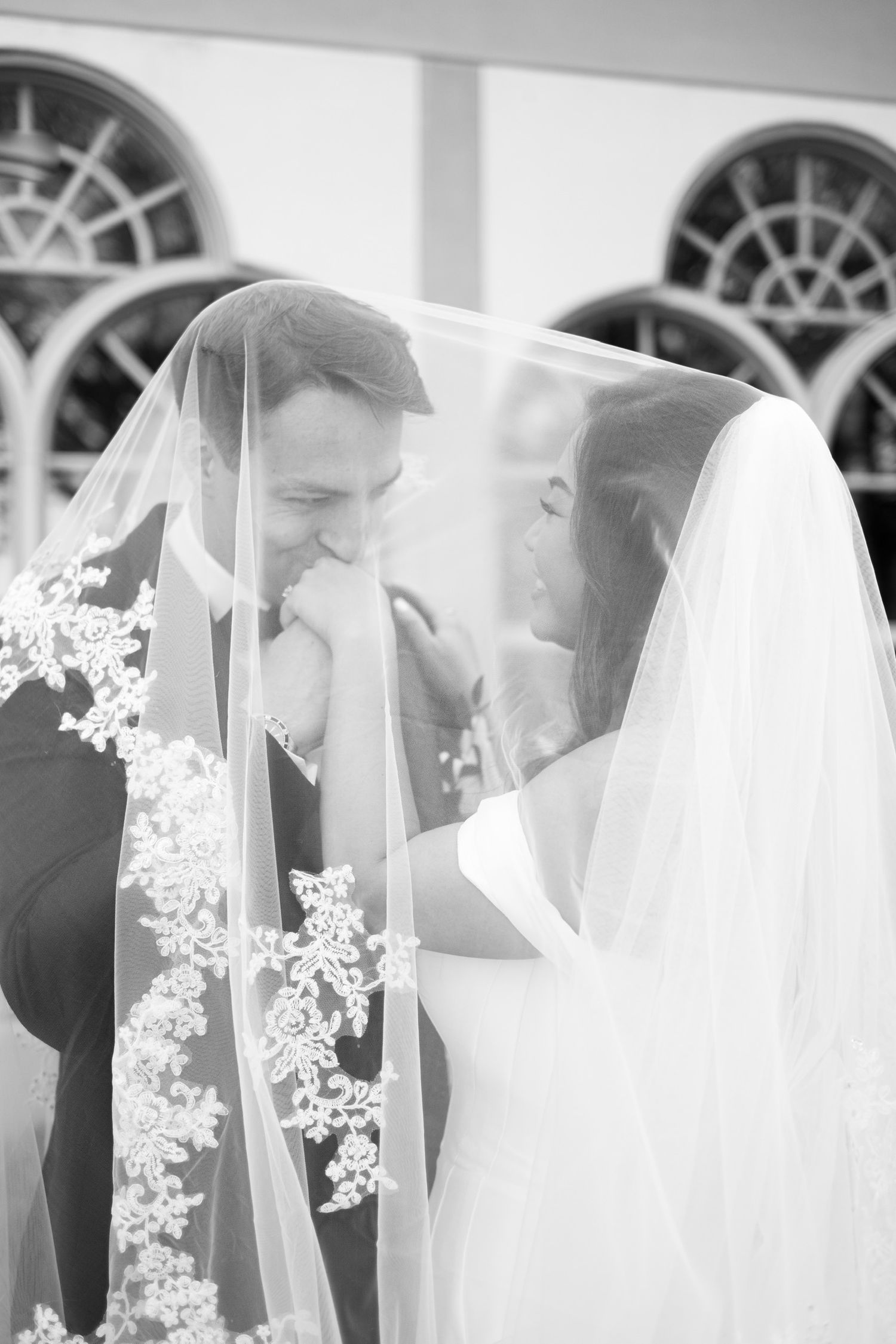 Black and white portrait series of couple sharing intimate moments through delicate veil.