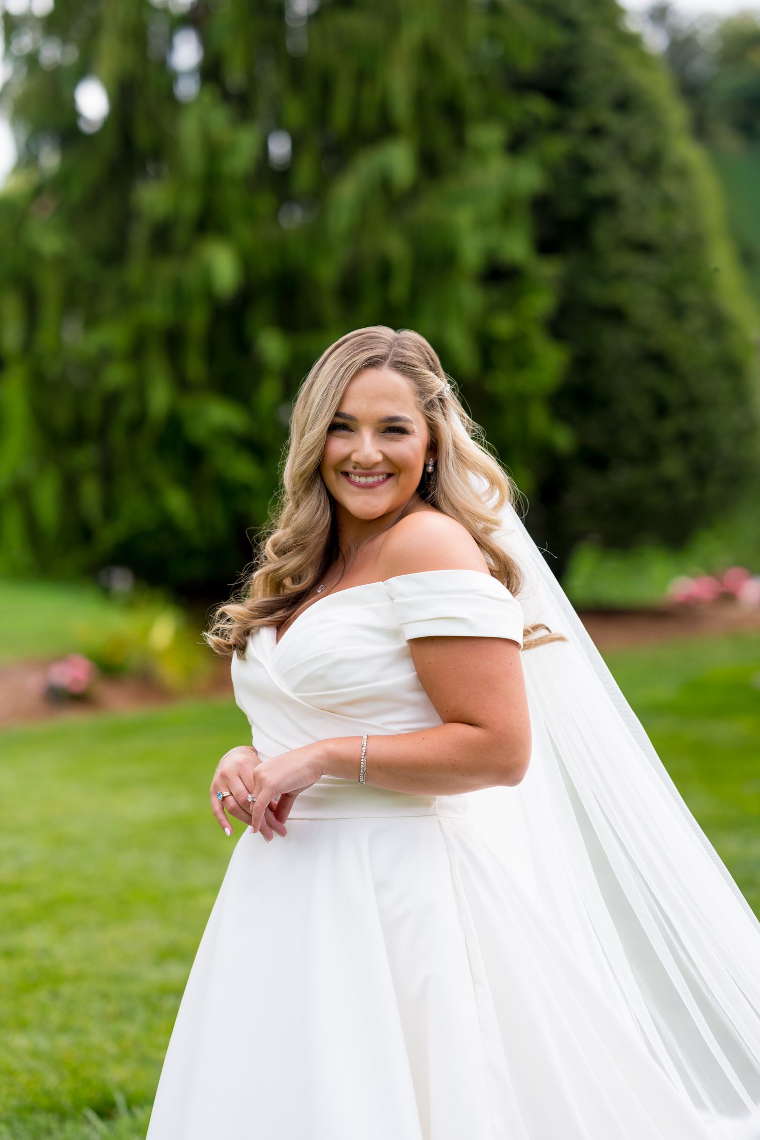 Outdoor bridal portrait in a white wedding gown with flowing veil.