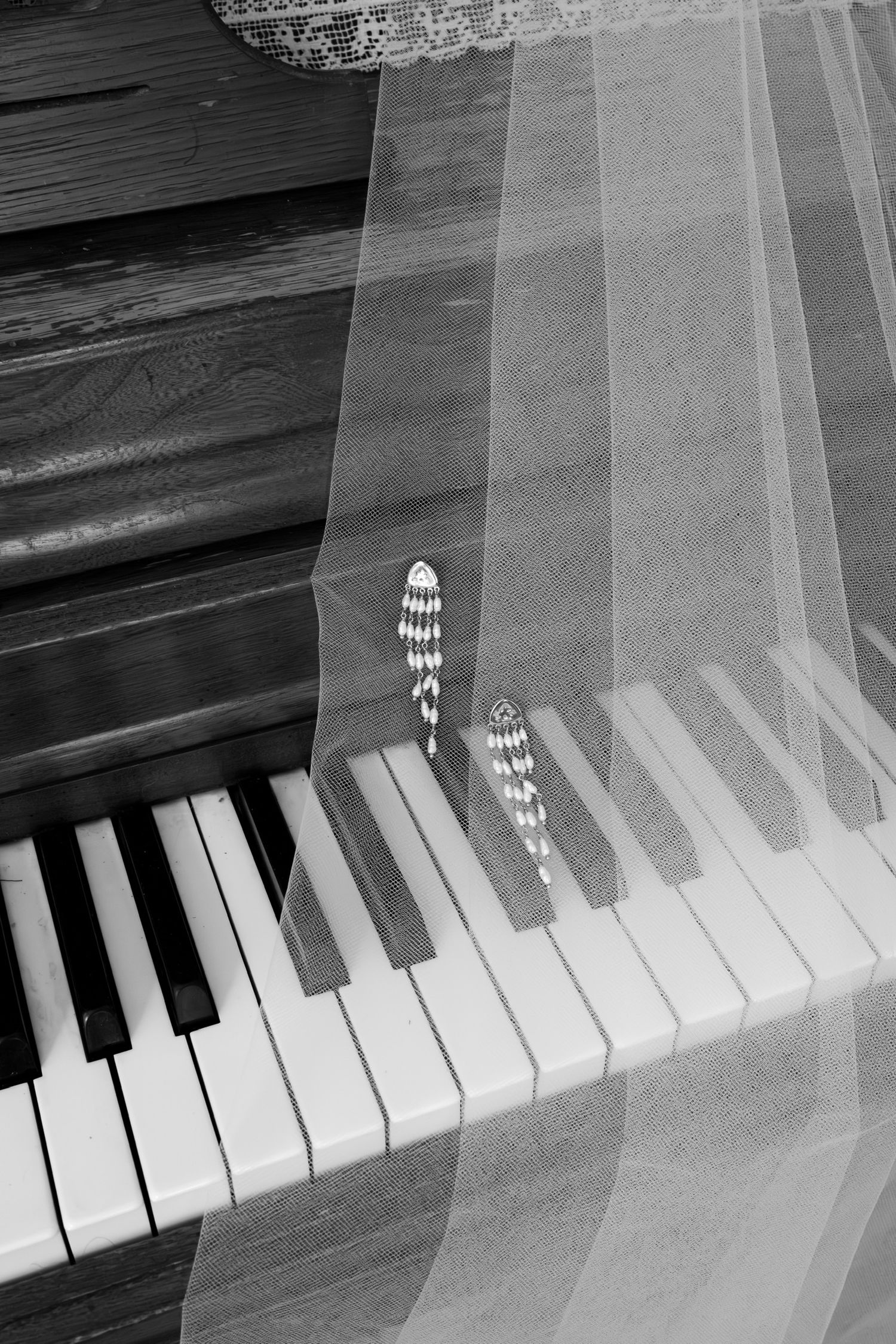 Sheer white veil draped over black and white piano keys creating an ethereal effect.