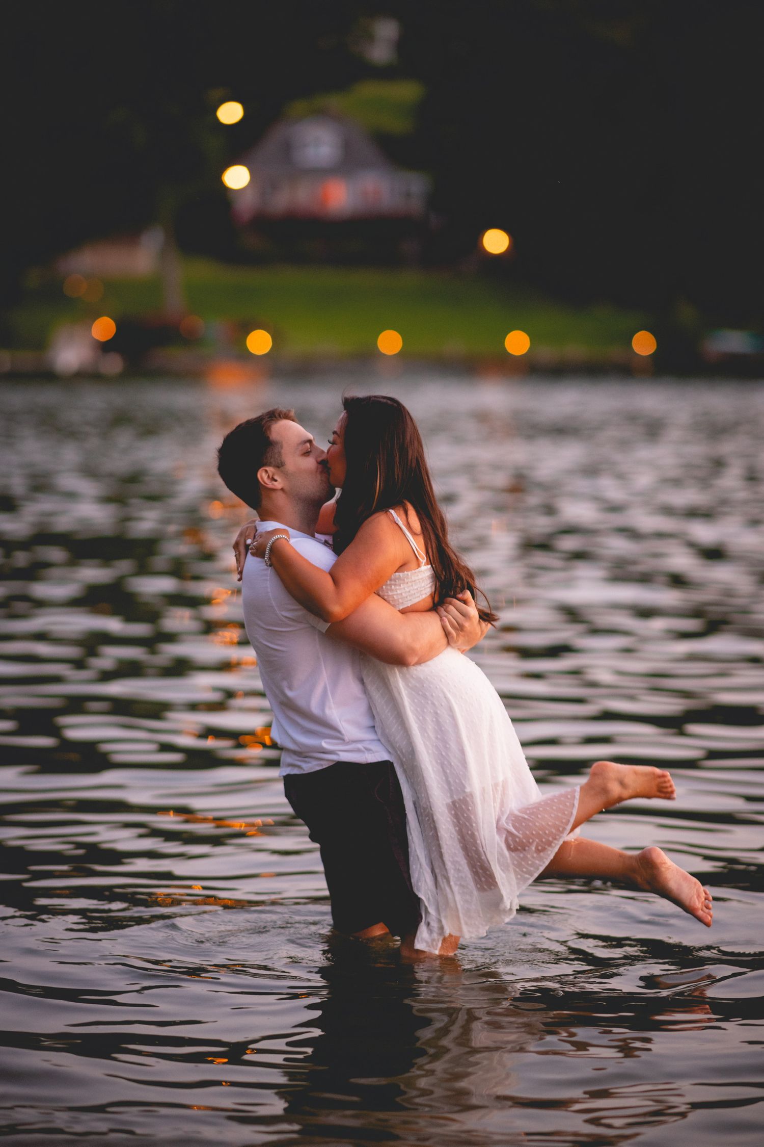 Romantic couple embracing while standing in Candlewood Lake during sunset.