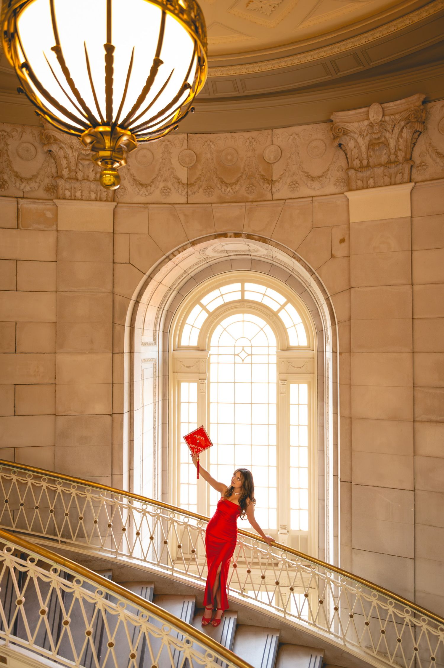 Elegant interior staircase with ornate details and natural lighting through arched windows for graduation photos at Hartford City Hall.