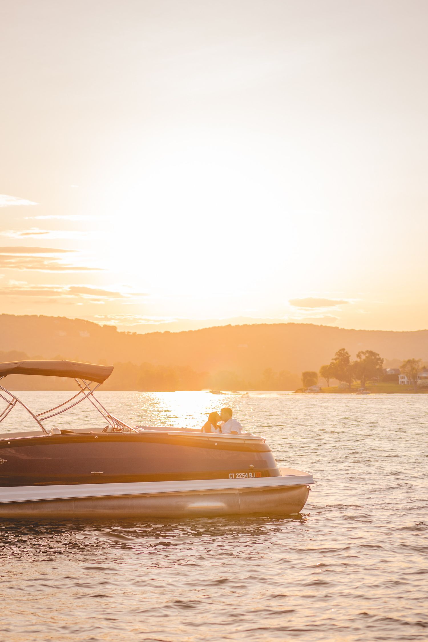 Boat floats on tranquil waters during a golden sunset with mountains silhouetted in the distance in Connecticut.