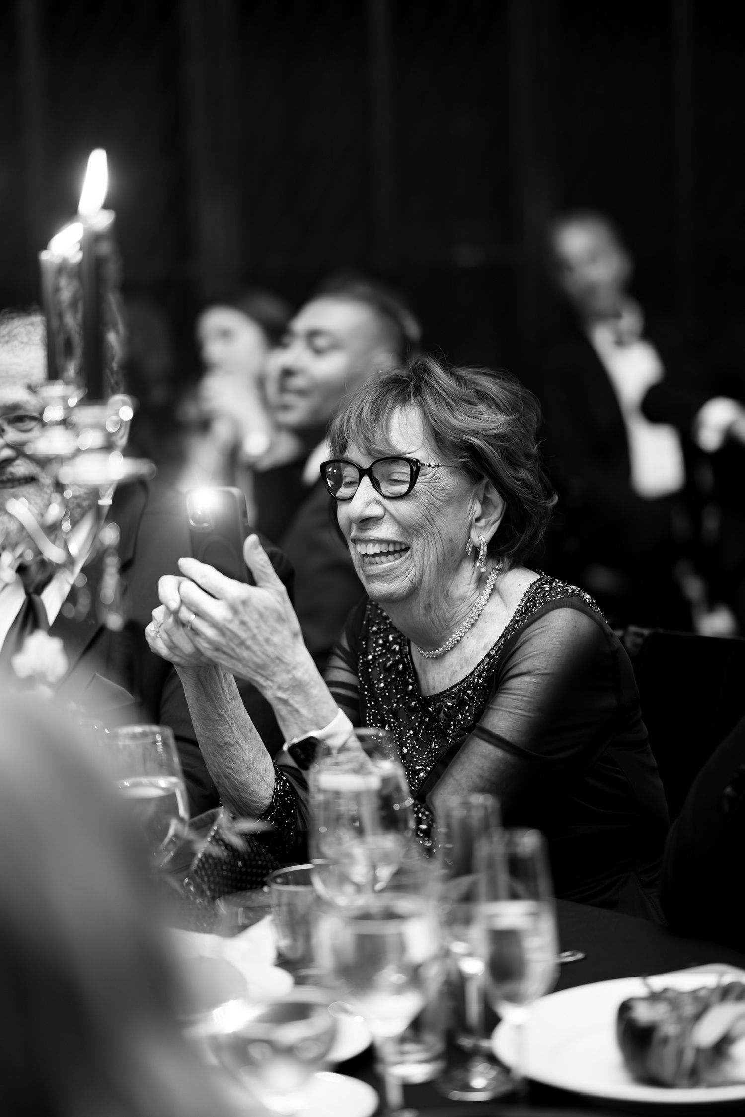 Wedding reception guests smile and laugh while enjoying dinner at Reid Castle in Purchase, New York.