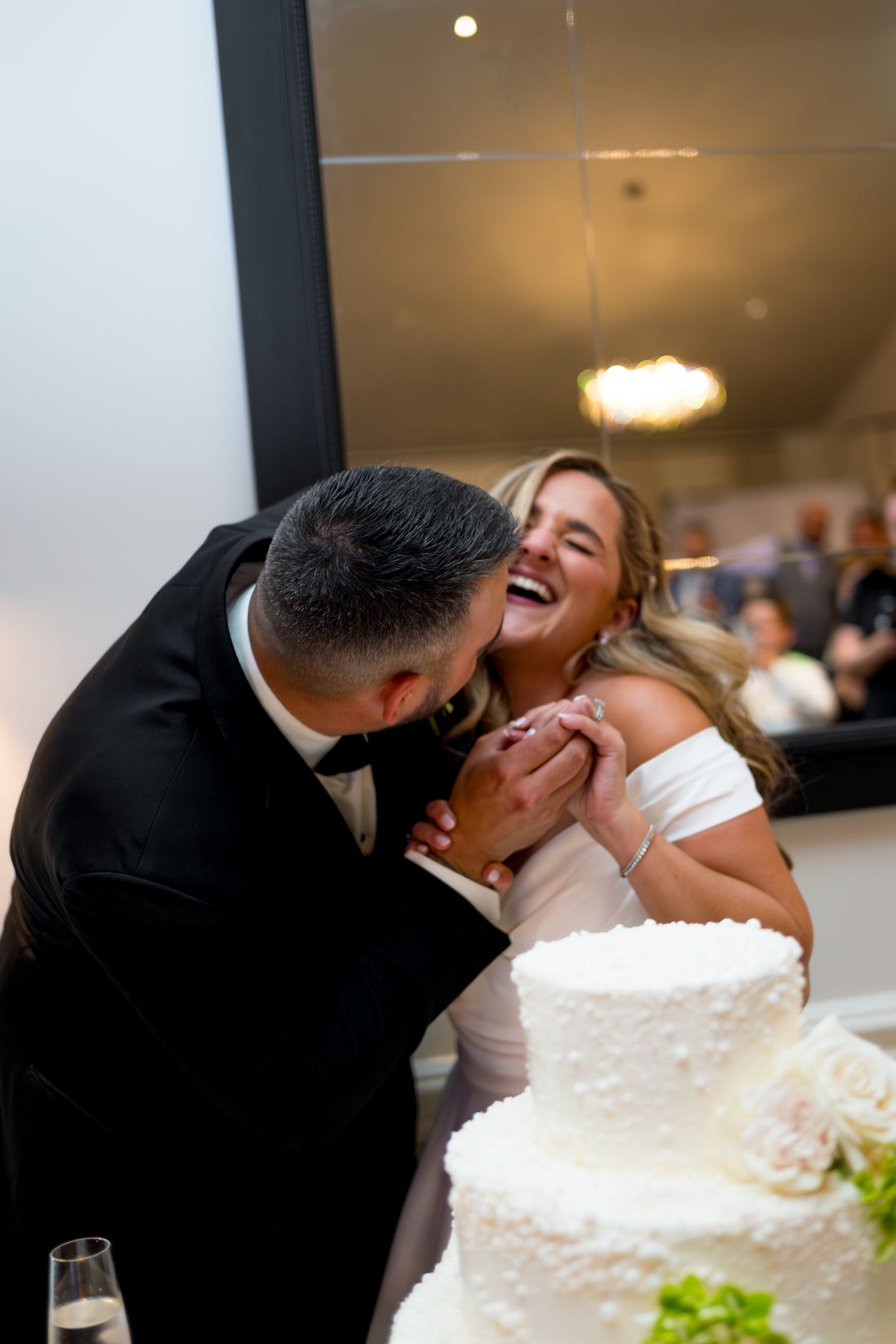 Newlyweds sharing a romantic moment while cutting their white wedding cake.