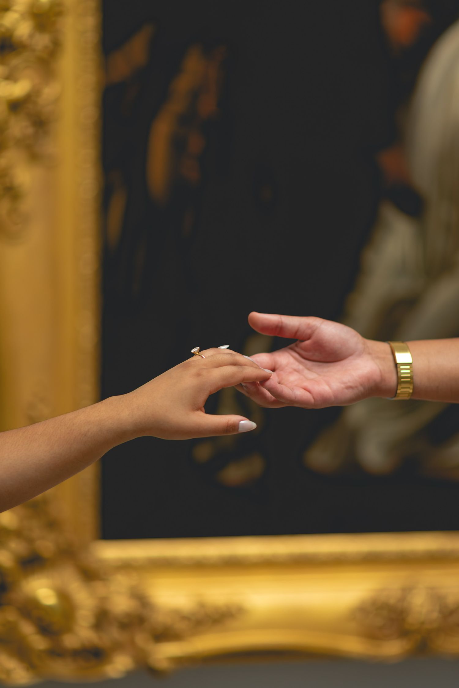 Close-up of hands exchanging wedding rings against golden background.