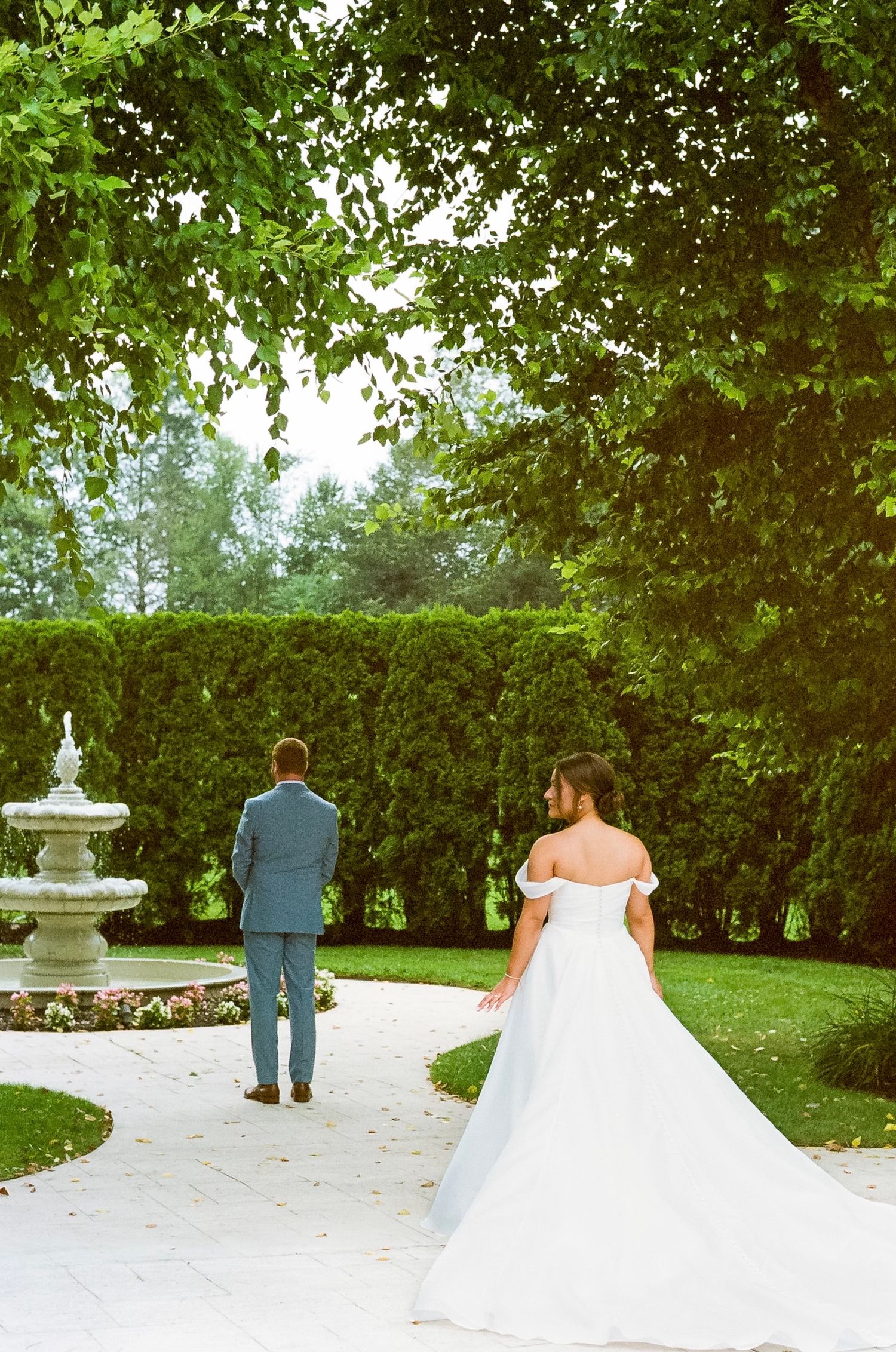 A sequence showing a first look wedding moment in a garden setting with a fountain.