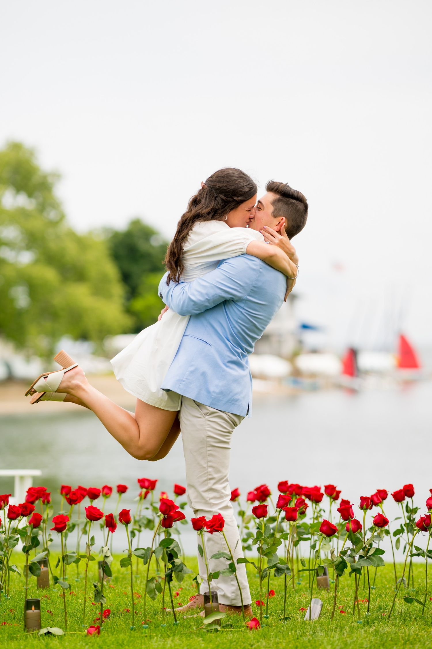 Romantic couple embraces in a field of red roses during proposal at The Inn at Longshore in Westport, Connecticut.