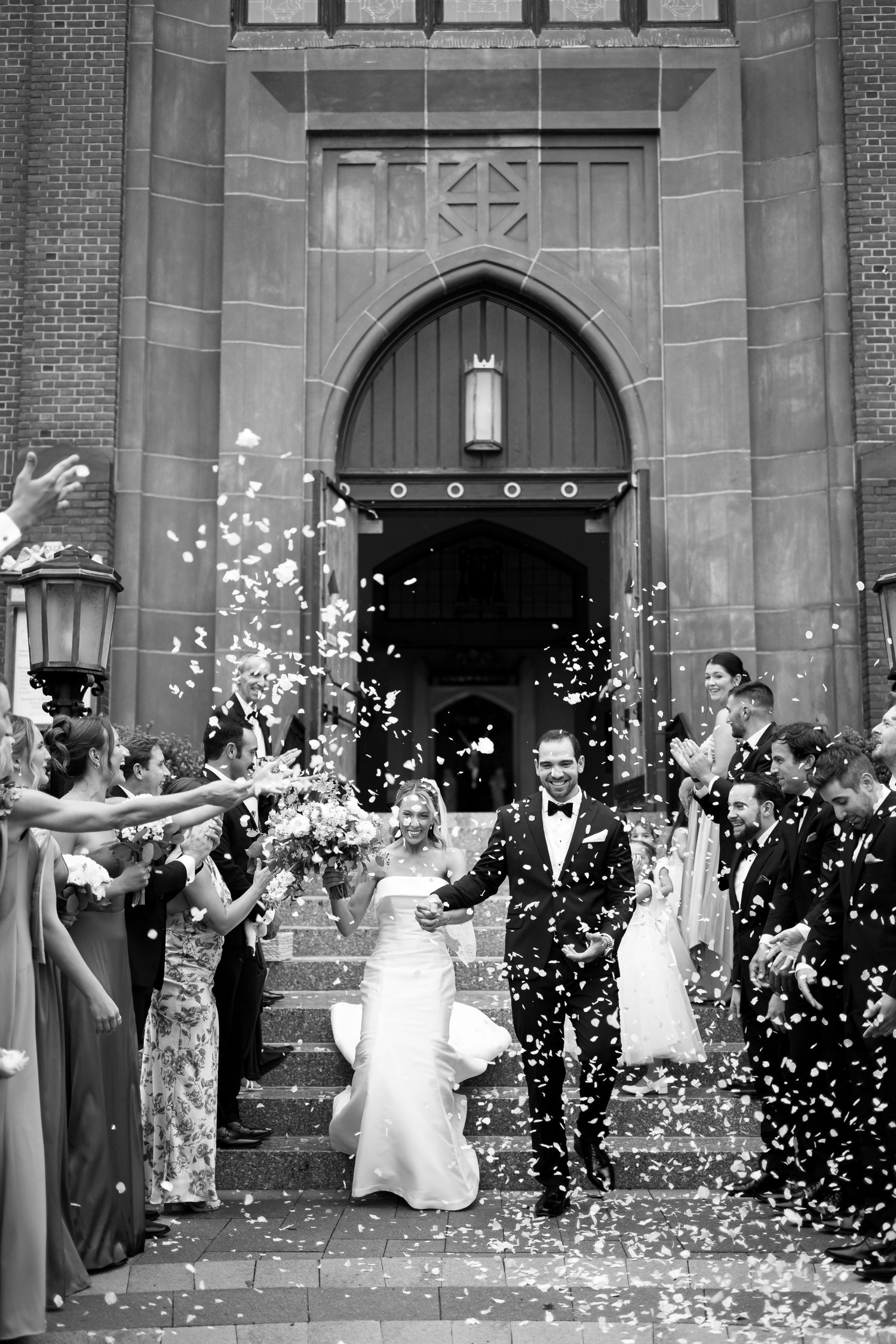 Joyful wedding celebration with guests throwing confetti outside church entrance.