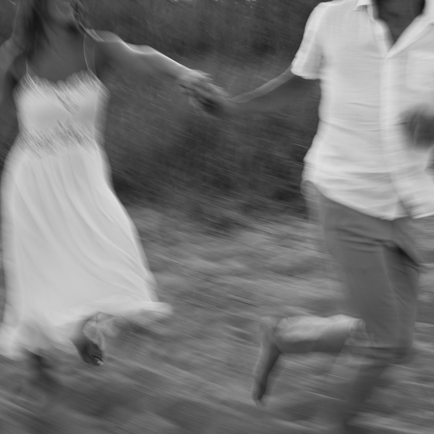 Motion-blurred black and white photo of a couple dancing outdoors.