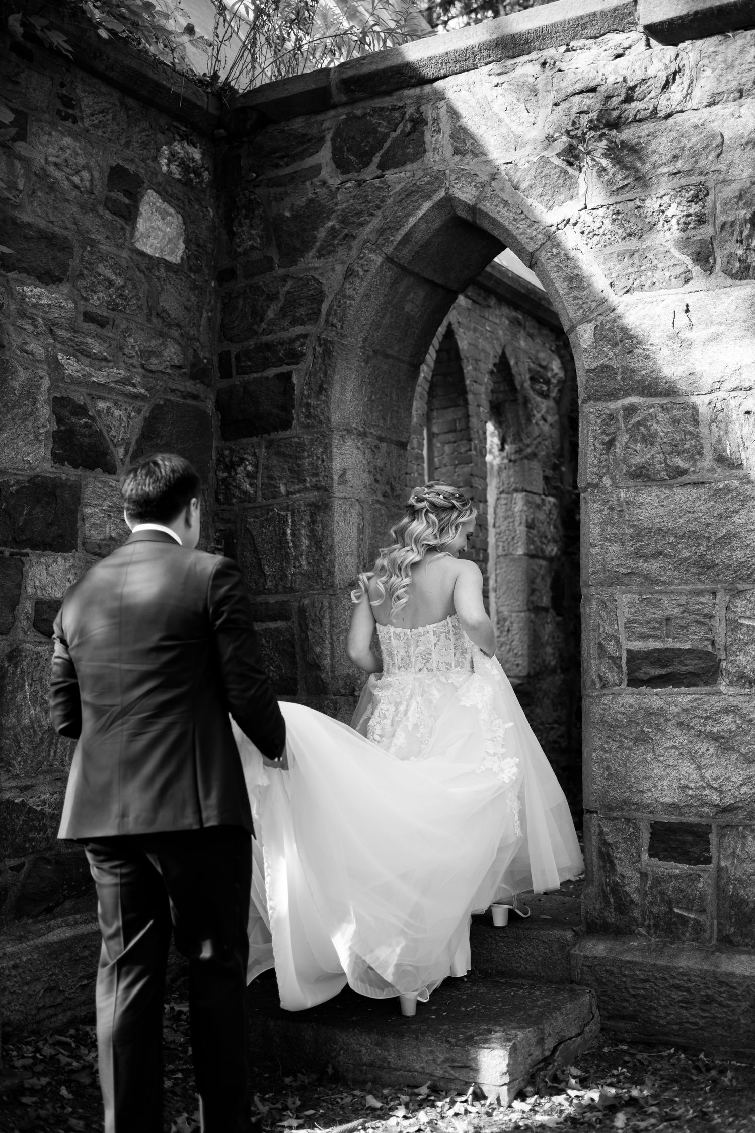 Wedding couple walking through stone archways and corridors in a historic castle setting.