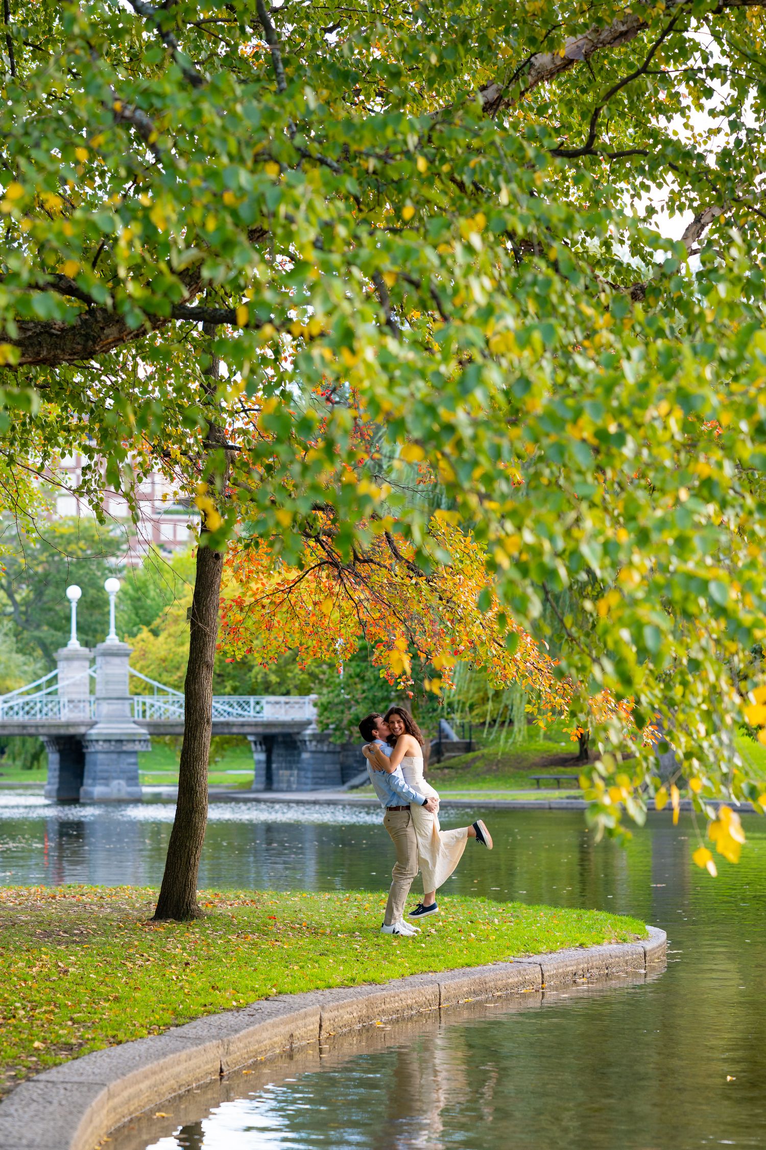 Romantic scene with stone wall and autumn foliage reflecting in water in Boston Public Gardens.
