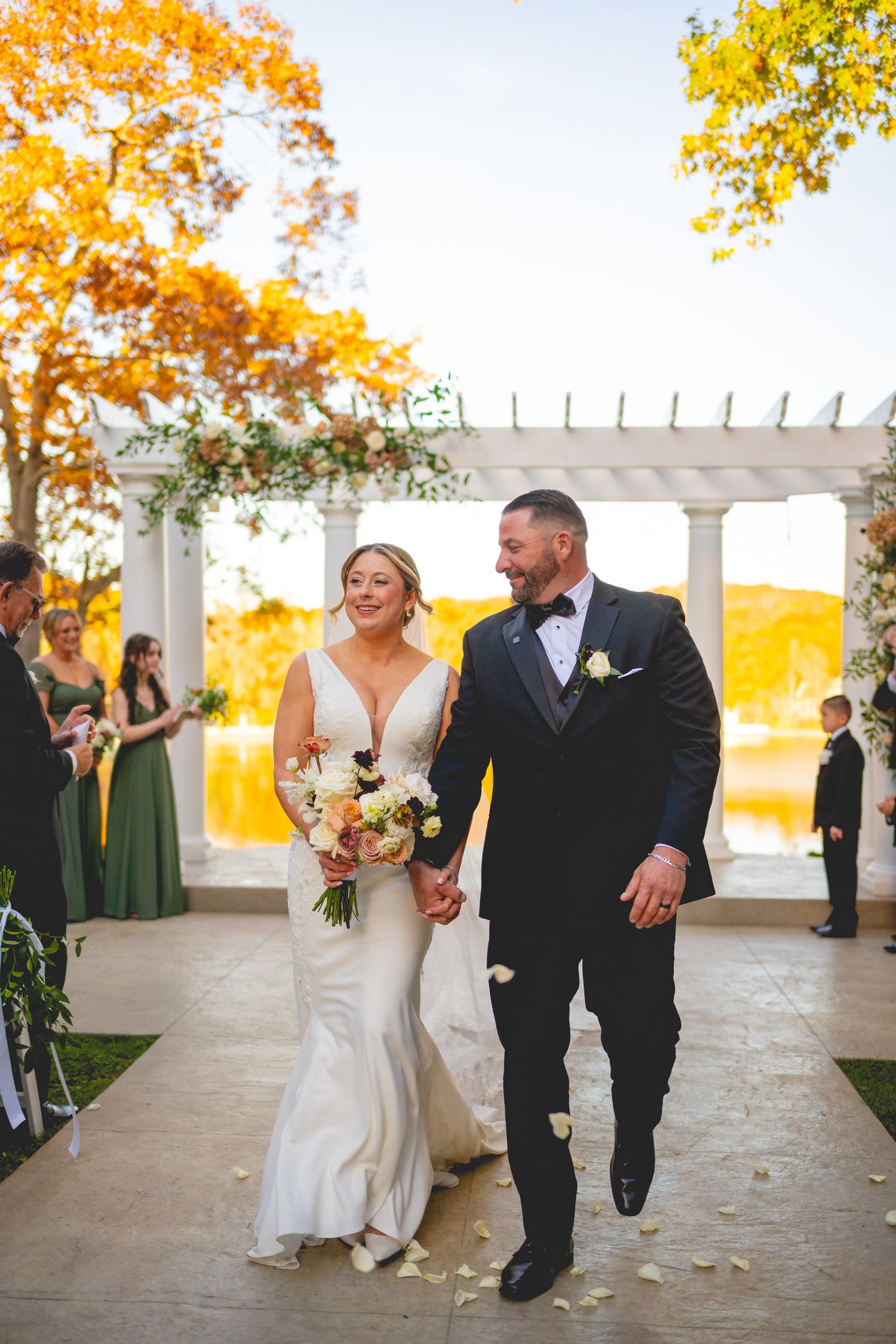 Bride and groom walking down the aisle with stunning fall colors in background at The Waterview in Connecticut.
