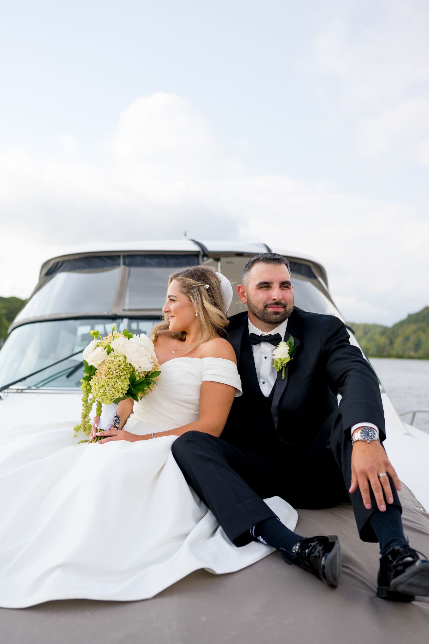Wedding couple relaxing on boat deck during waterfront photo session.