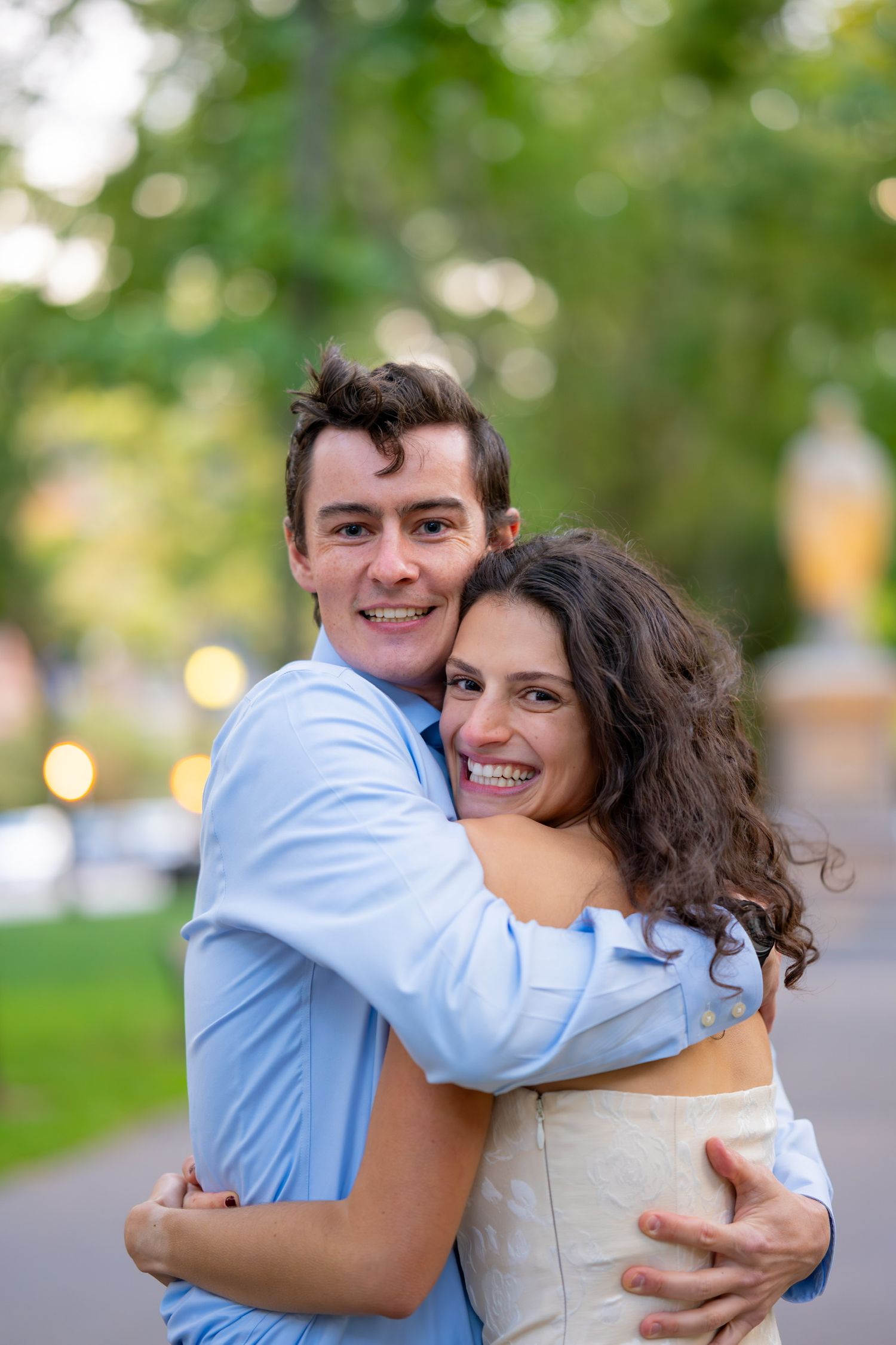 Joyful embrace captured outdoors with soft natural bokeh background in Boston, Massachusetts.