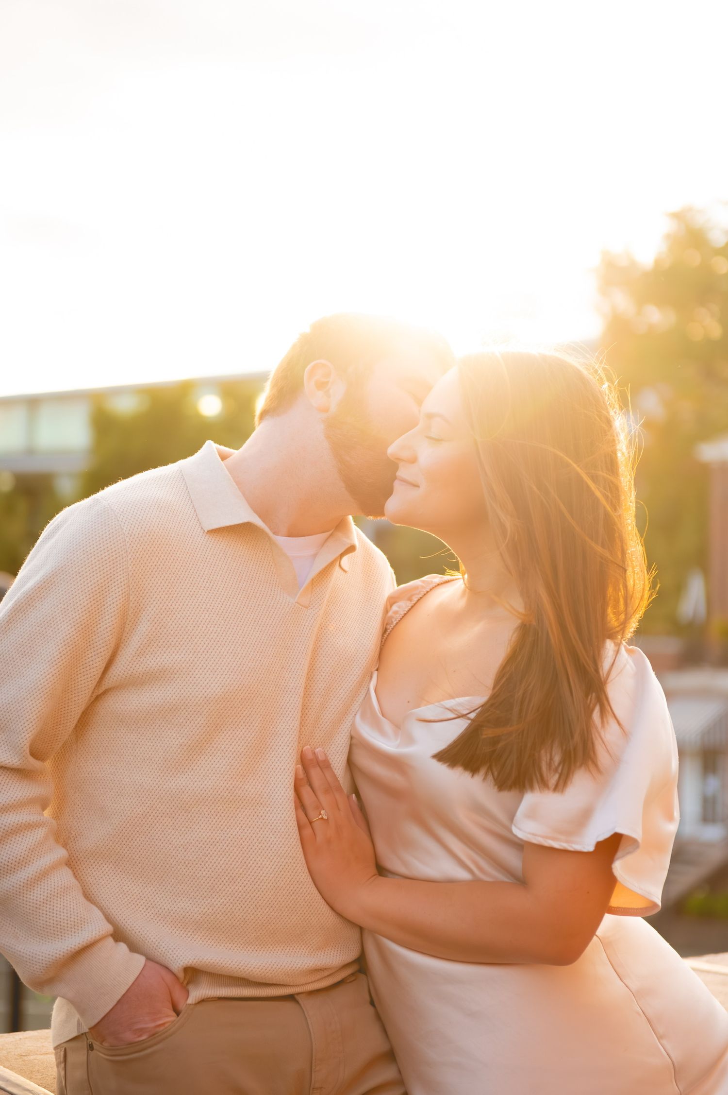 Couple embracing during golden hour sunset photo session in soft warm light.