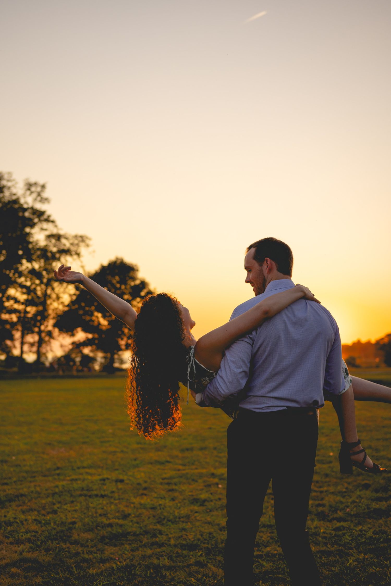 A couple shares an intimate dance in a golden field during sunset.