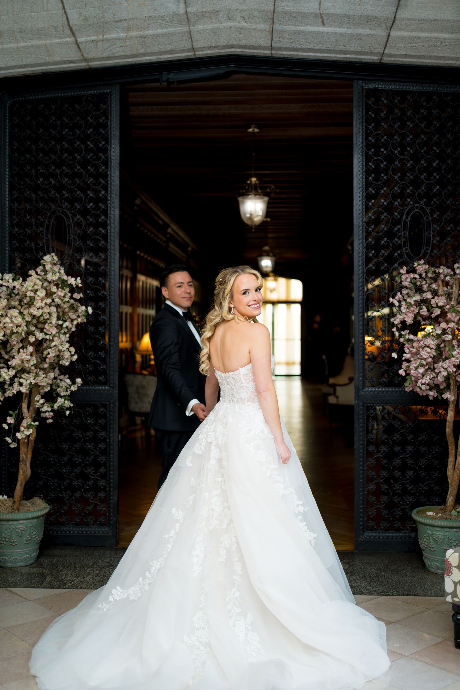 A bride in a flowing white gown twirls through an elegant venue decorated with cherry blossom trees.