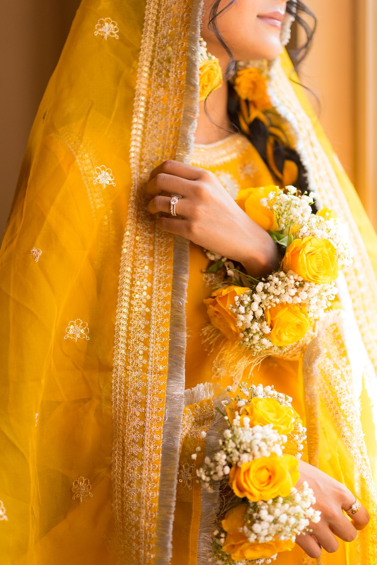 Detailed view of a yellow traditional Indian bridal outfit with delicate floral accents.