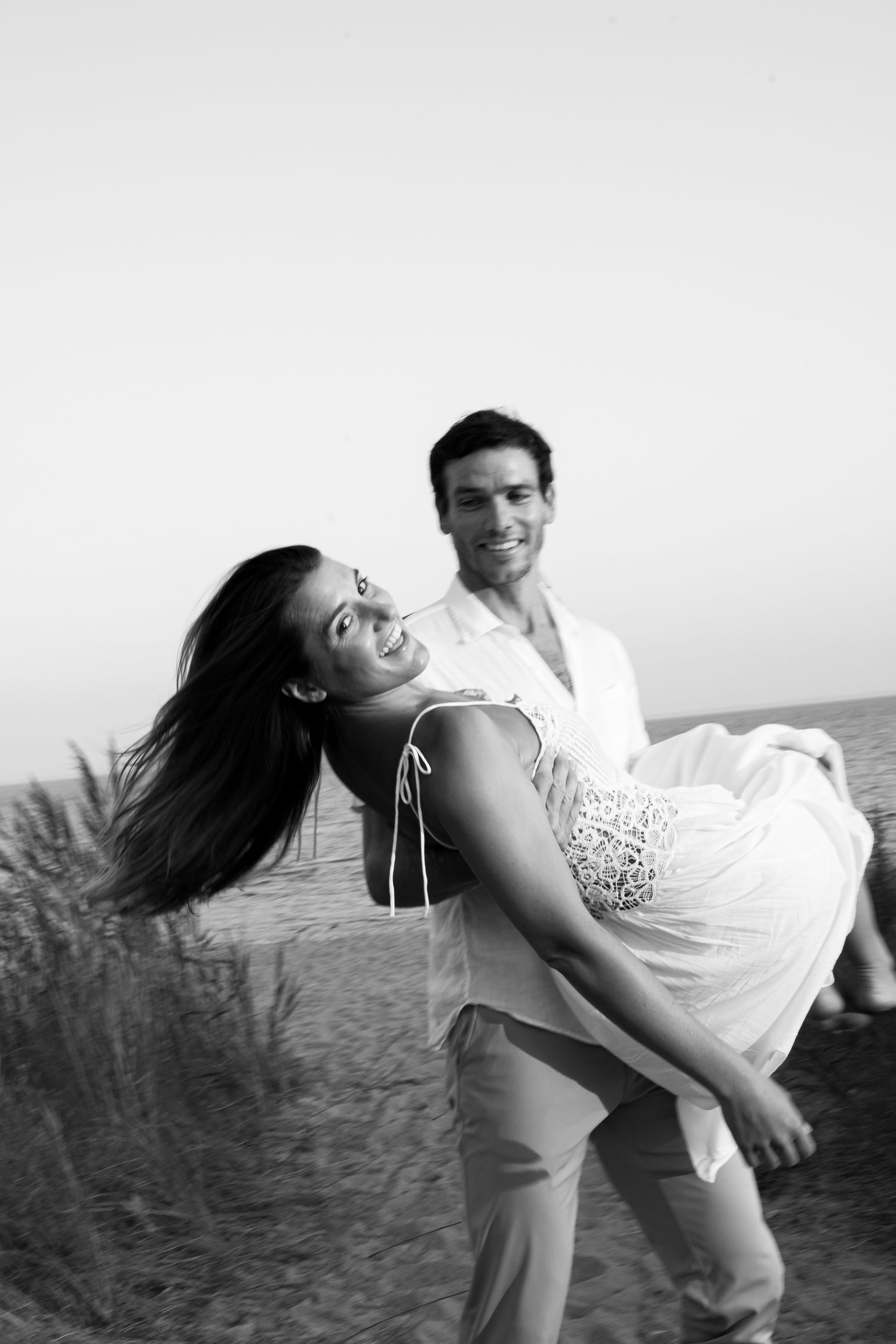 A playful black and white photo of a couple enjoying a romantic moment by the beach.