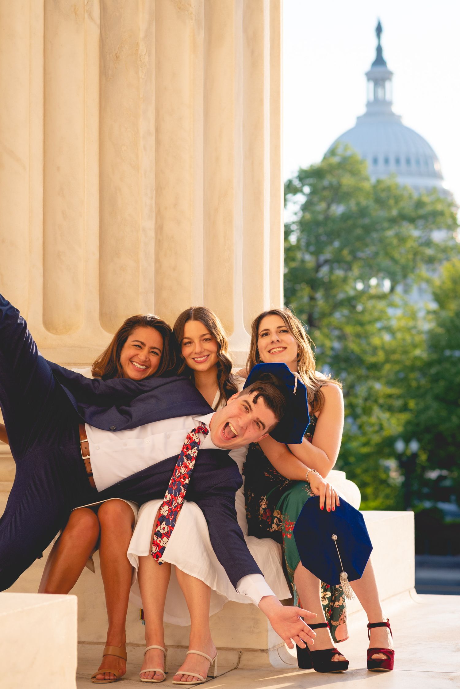 Group posing playfully between columns with the US Capitol dome visible in background.