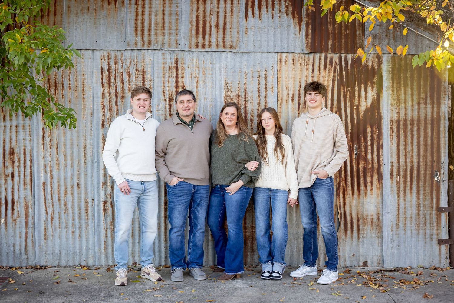 Five people sit together against a metal corrugated wall background.