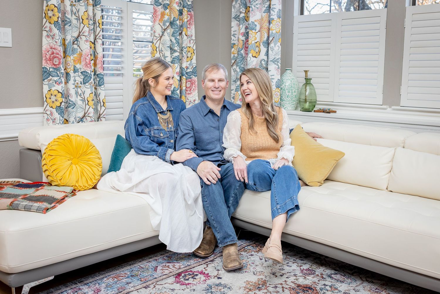 Family relaxing together on white sectional sofa in modern living room setting.