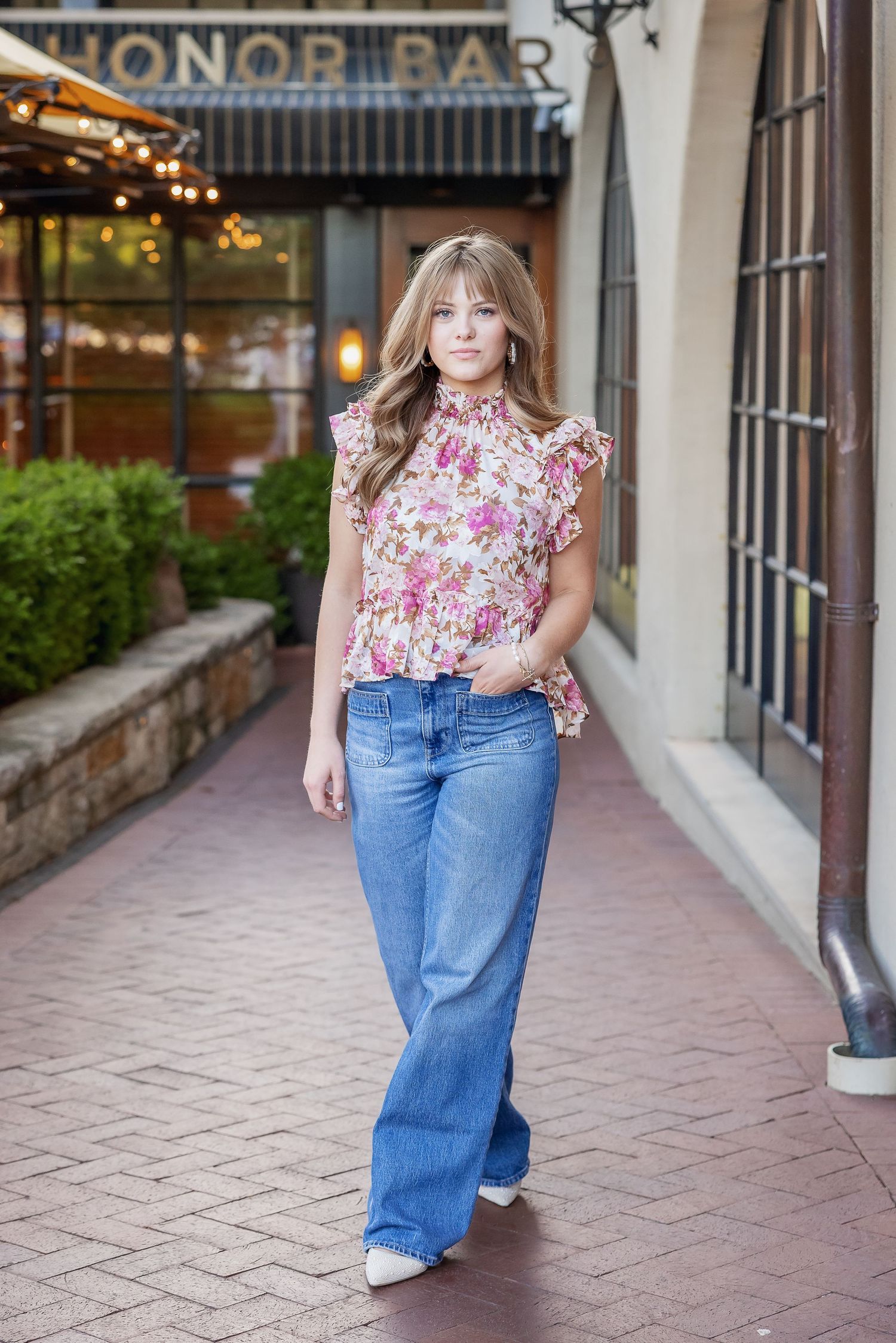 Stylish floral ruffle blouse paired with wide-leg jeans in front of Honor Bar storefront.