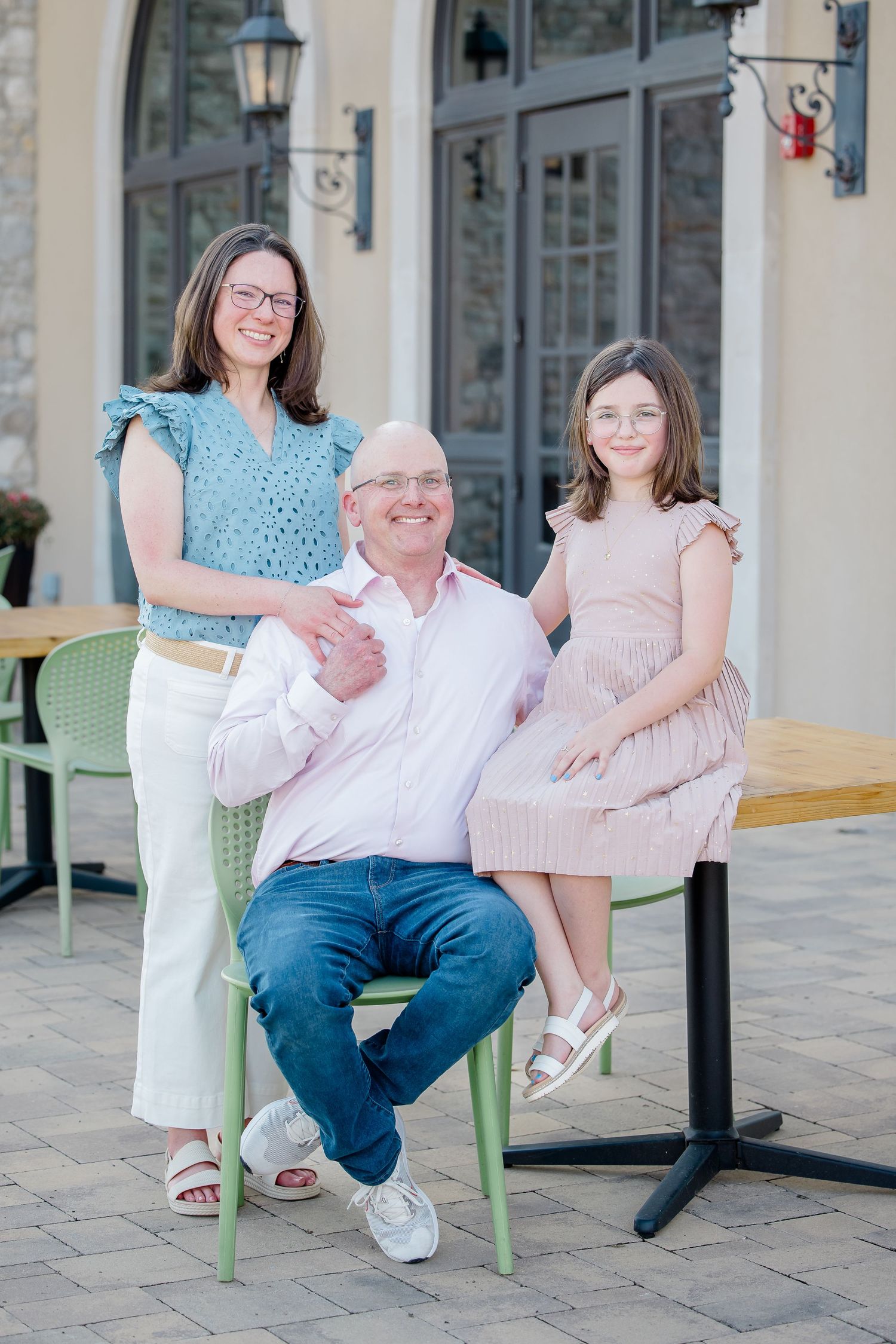 A casual outdoor portrait of three people sitting at a cafe patio.