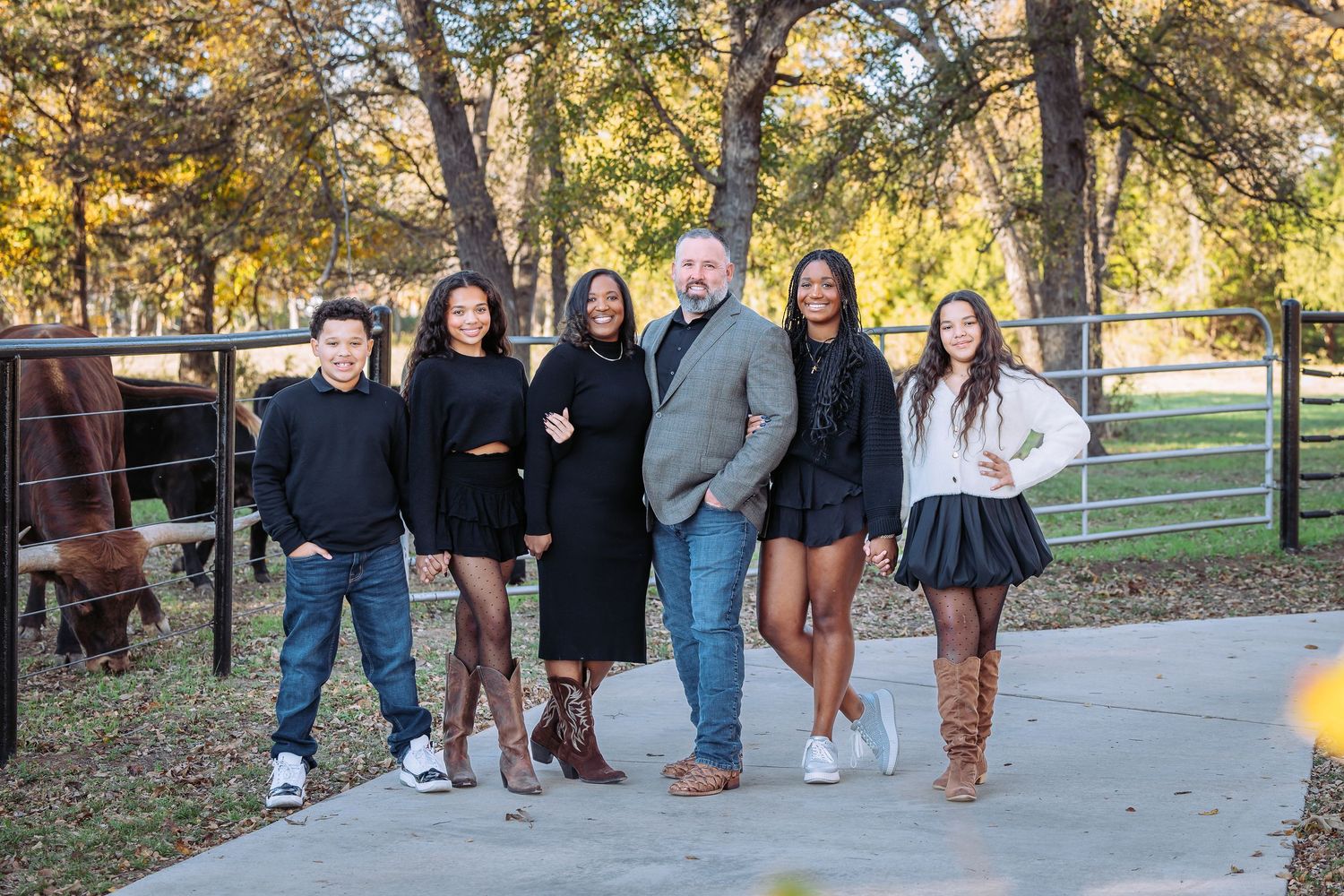 Group of friends in casual attire posed together on outdoor pathway during autumn.