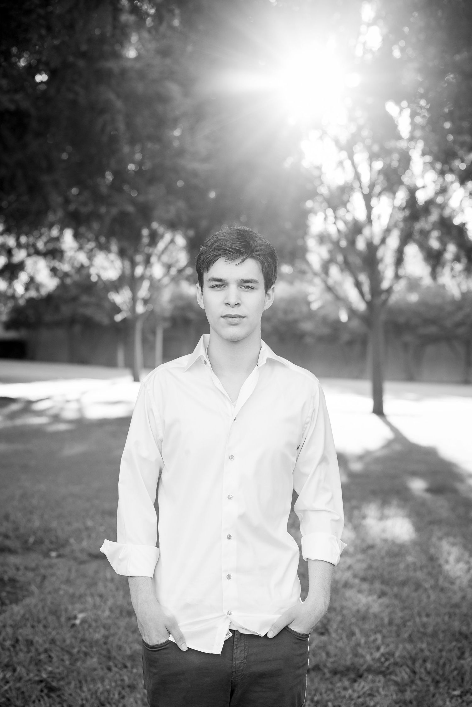 Outdoor portrait against trees with bright sunlight creating a backlit effect.