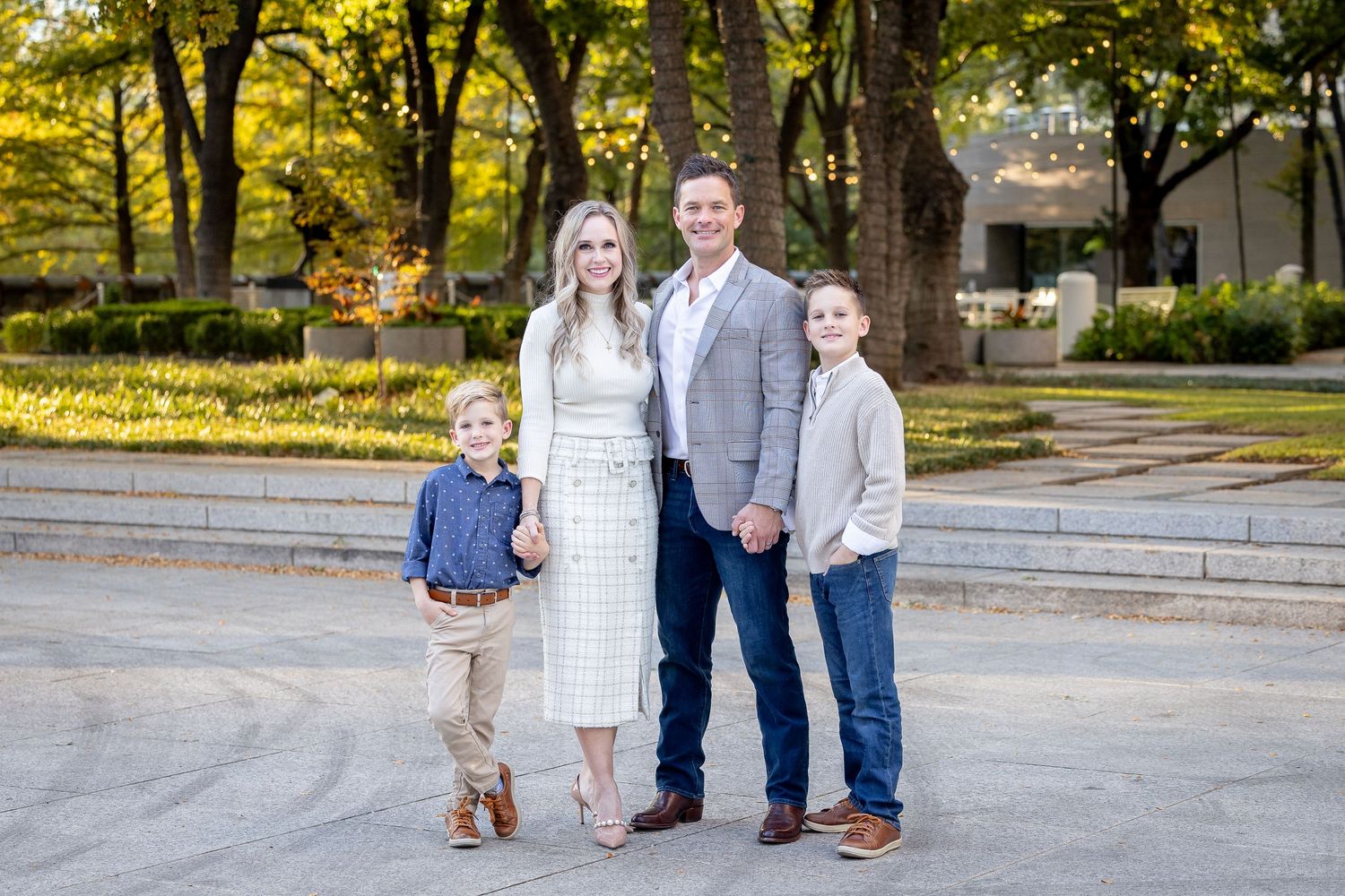 Family wearing coordinated blue outfits poses together on grass during golden hour photoshoot.