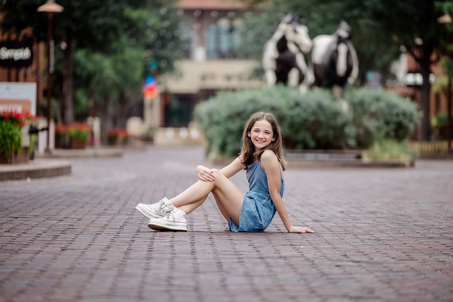 Young woman in jean shorts lying on stone paving blocks in an artistic outdoor portrait session.