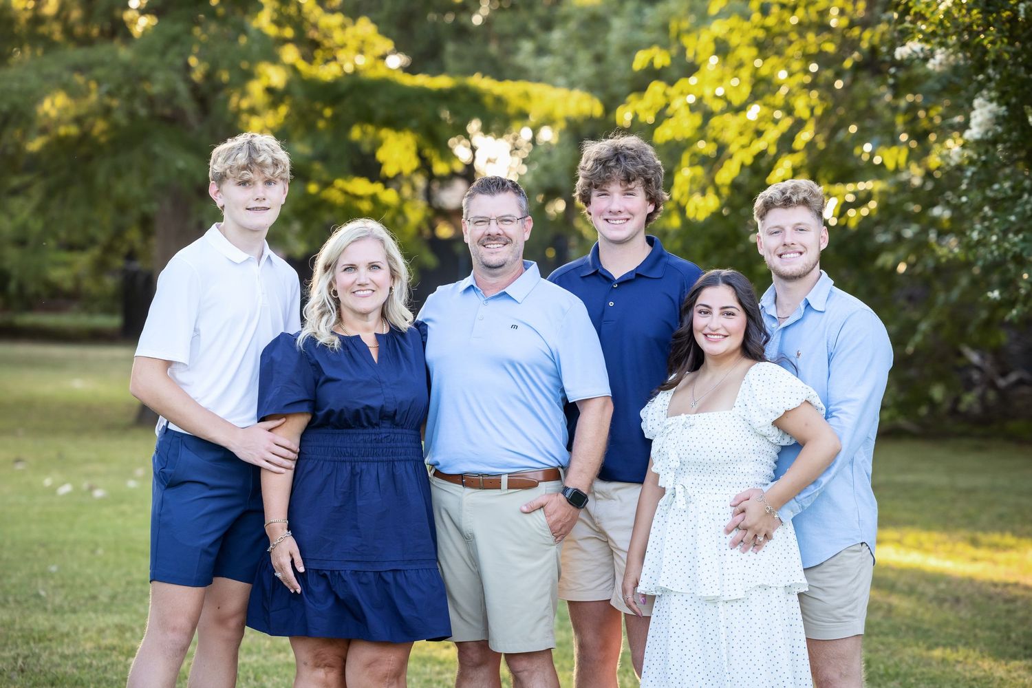 Extended family group photo outdoors wearing coordinated navy and white outfits.