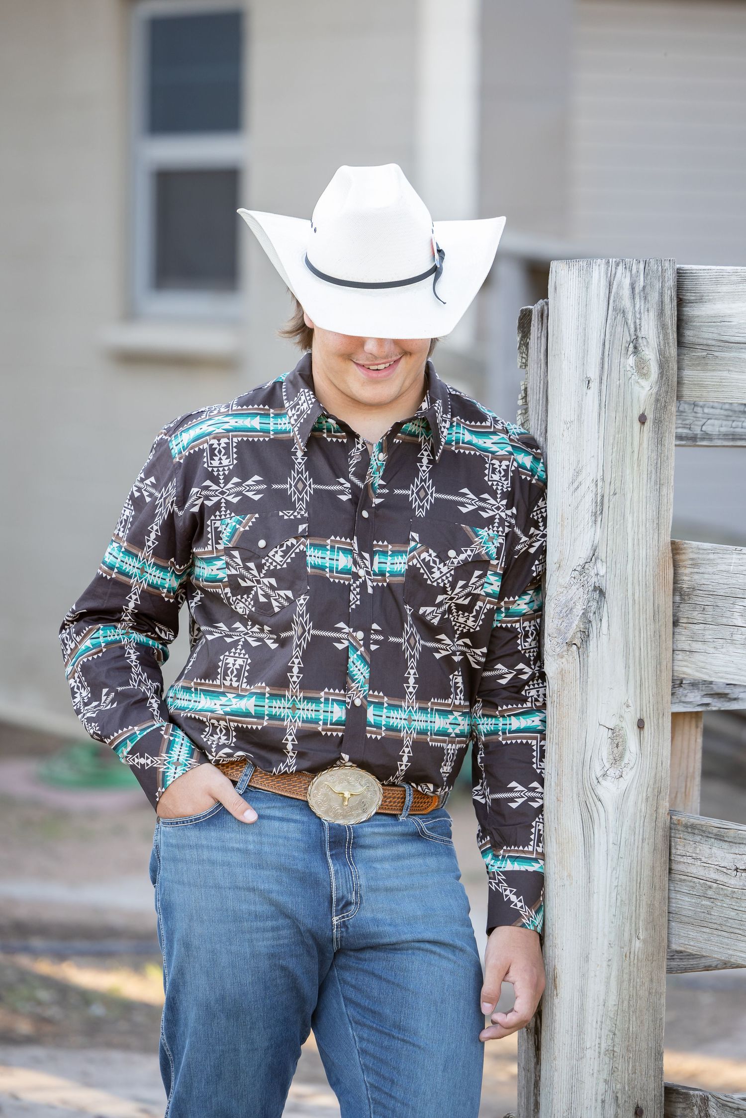 Western-style pattern shirt with turquoise details paired with blue jeans and a large belt buckle.