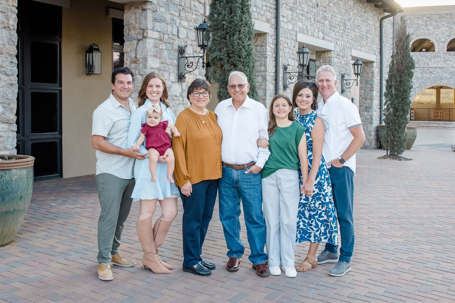 Extended family group poses together outside a stone building entrance.