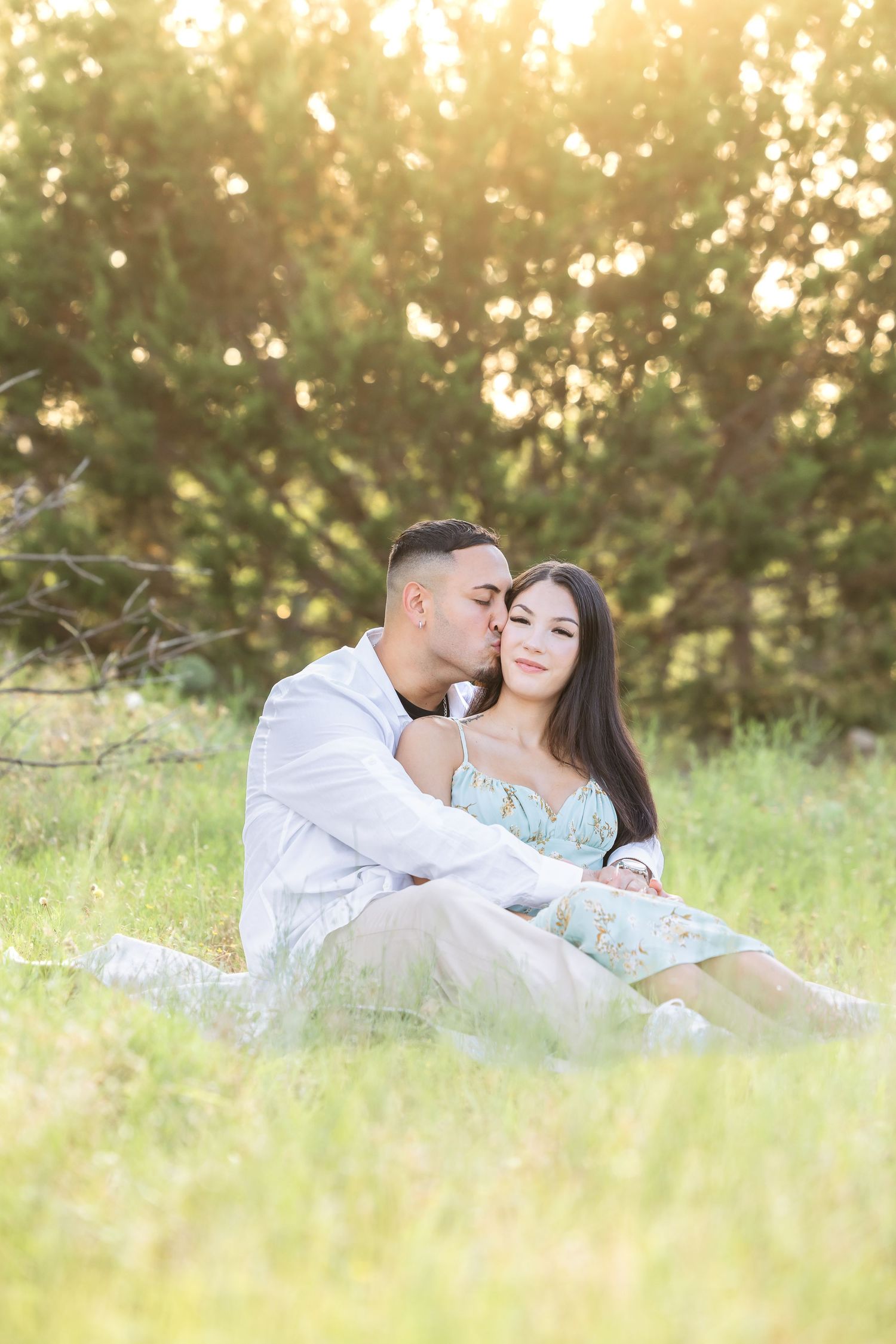 A couple shares a romantic moment in a sunlit field during golden hour.