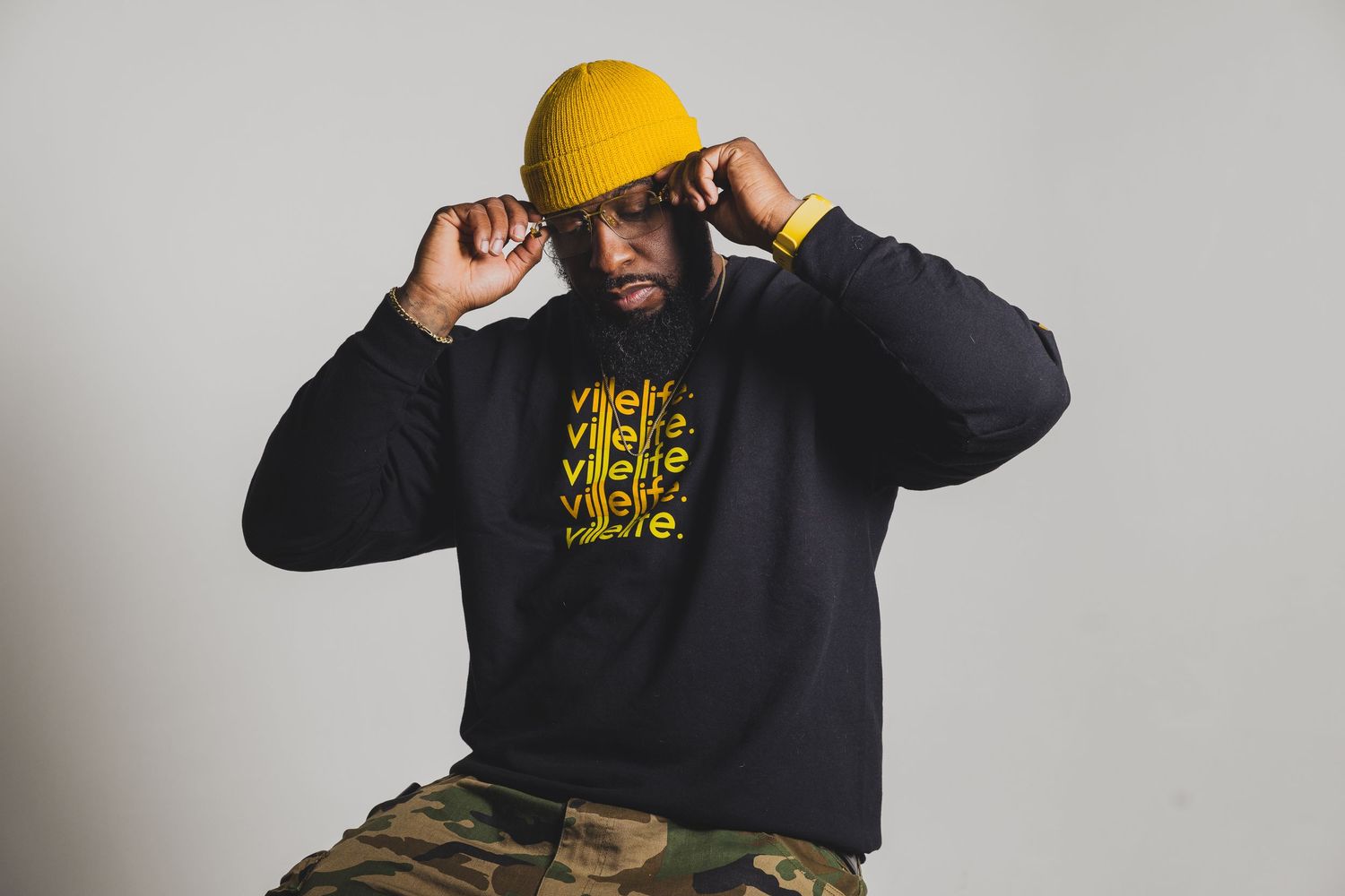Person adjusting yellow hard hat while wearing black sweatshirt with graphic print.