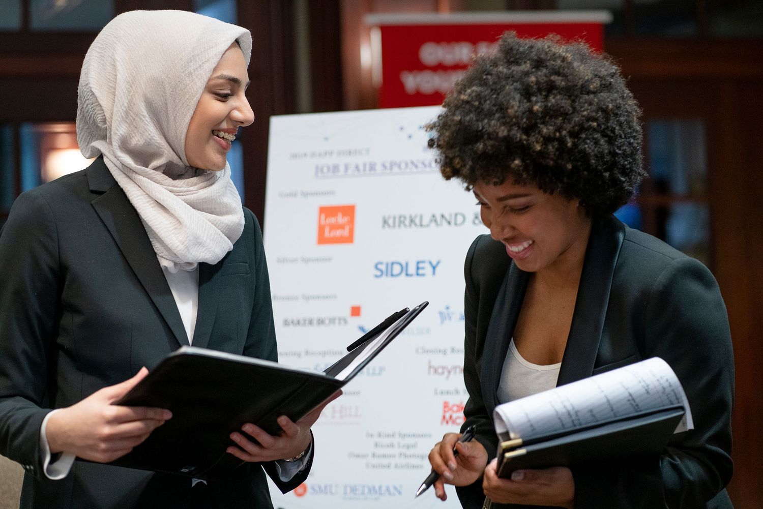 Two professionals reviewing documents together at a business networking event.