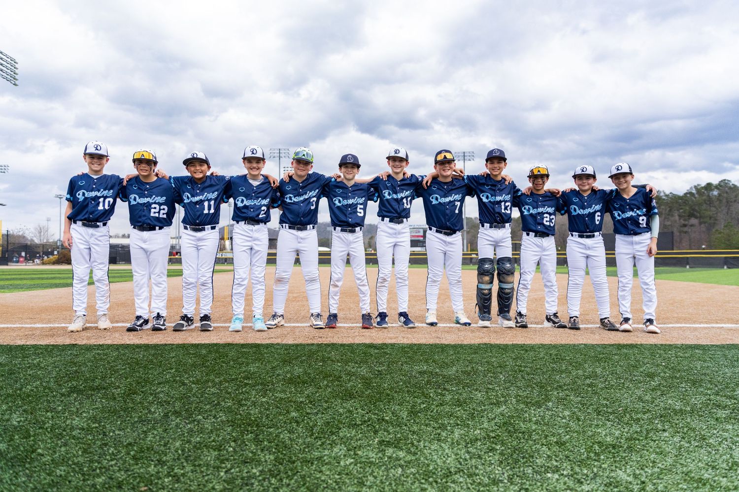 Baseball team in navy uniforms lines up for team photo on field.