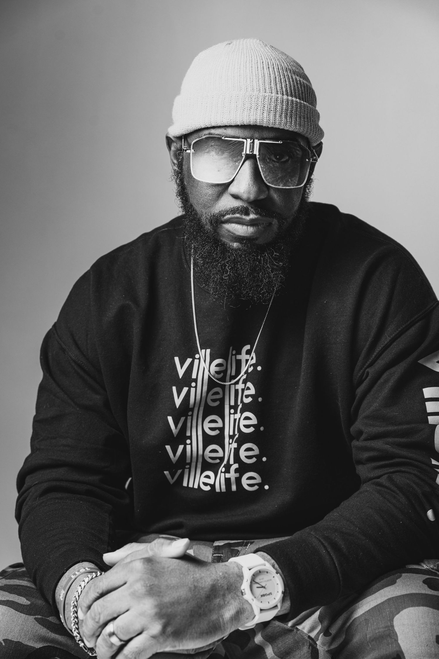 Urban portrait of person in winter beanie and glasses wearing streetwear with repeated text design.