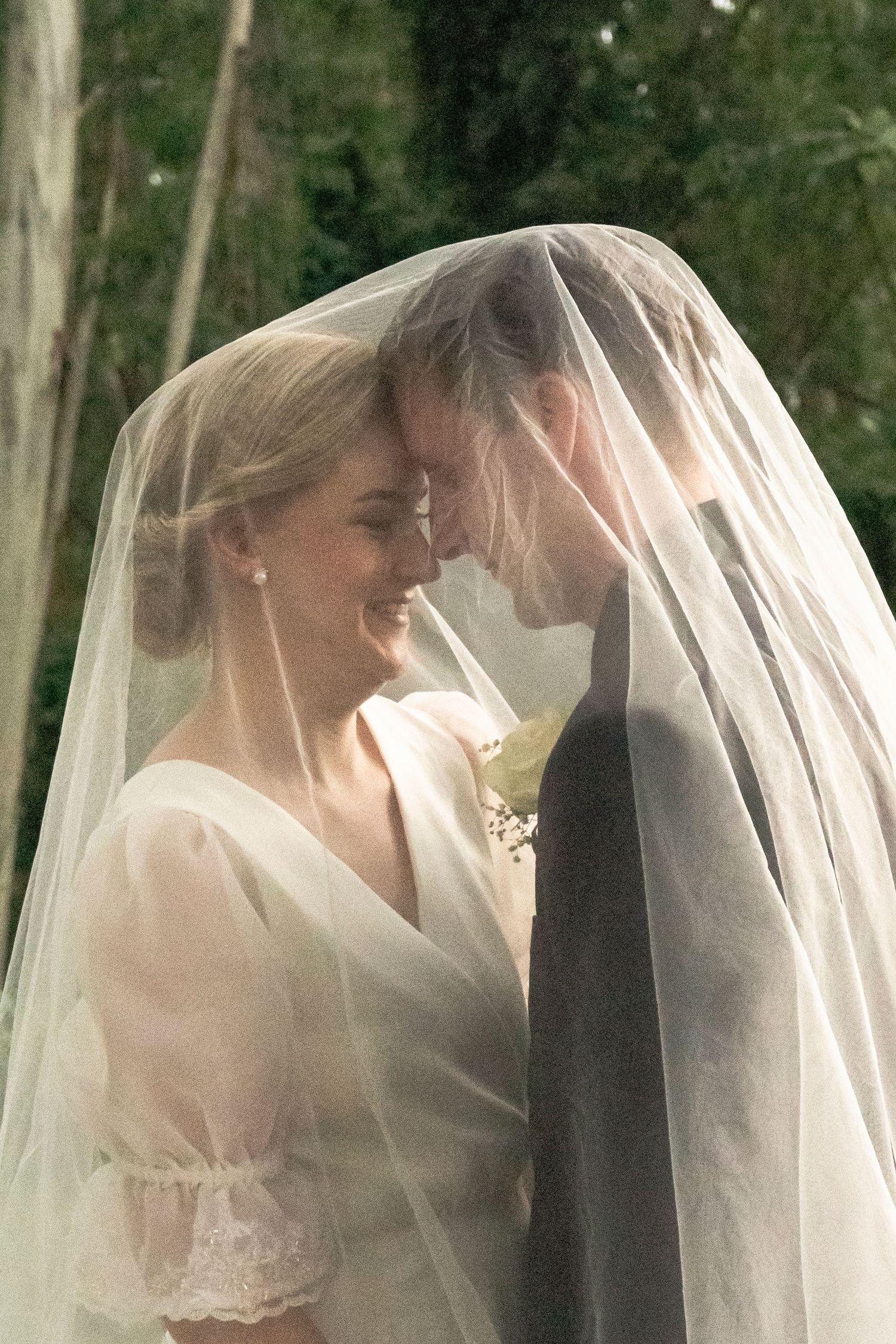 Bride and groom embracing closely under a veil in a romantic wedding portrait
