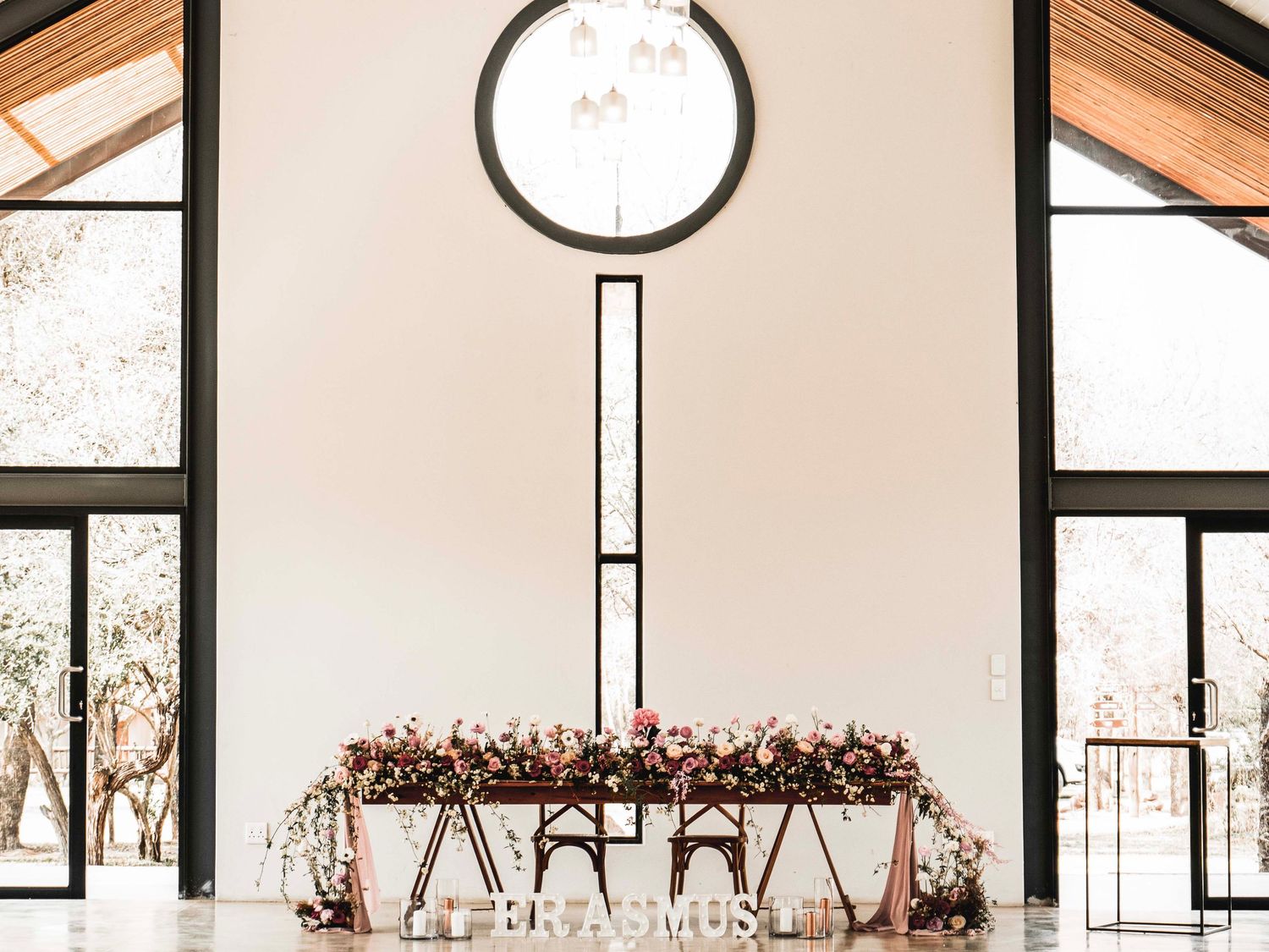 Wedding ceremony altar decorated with florals beneath a round window