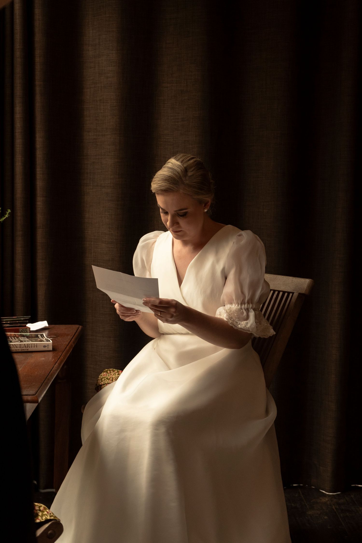 Bride reading a letter while seated indoors before the wedding
