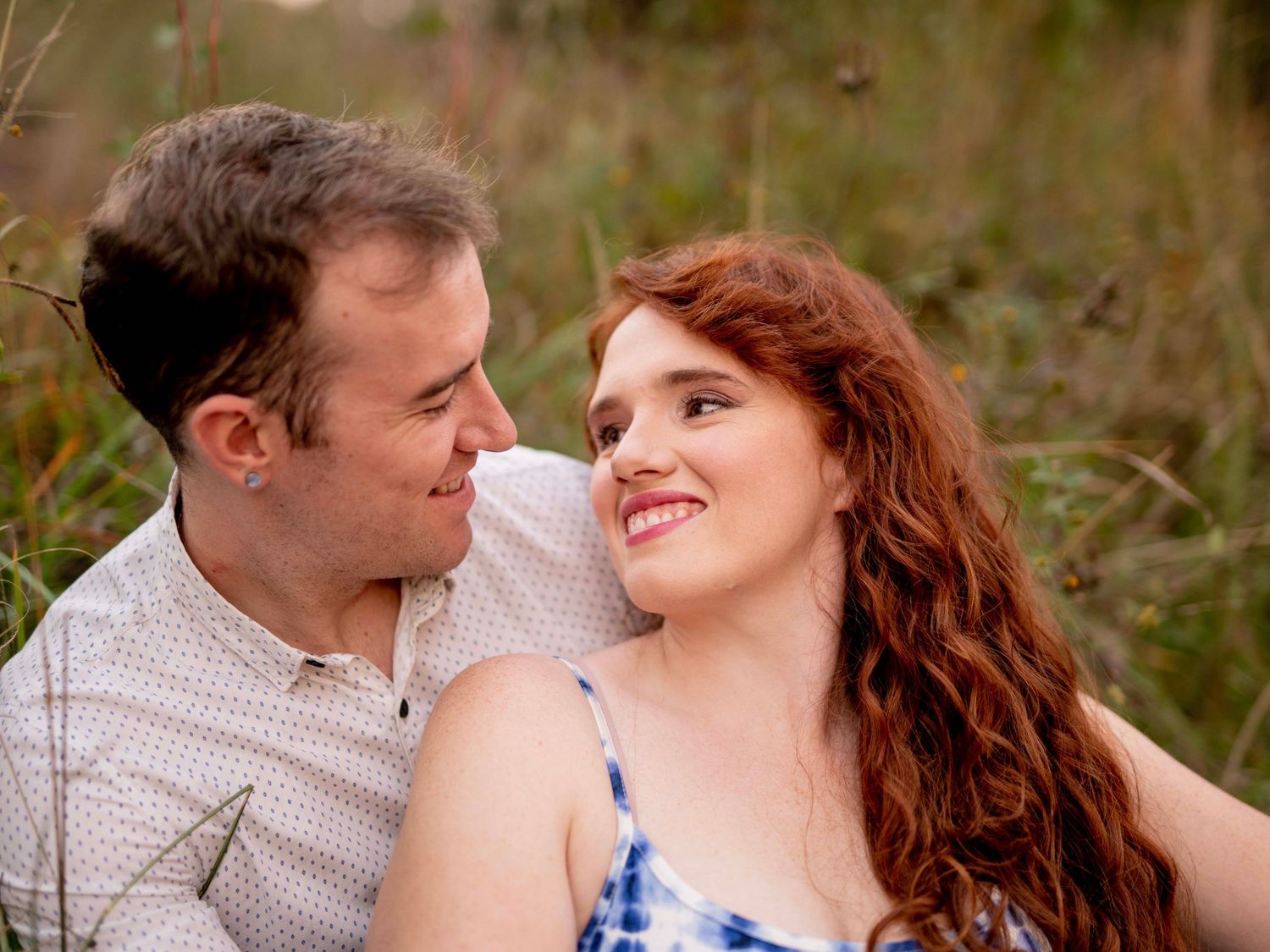 Couple smiling closely at each other outdoors during their engagement session