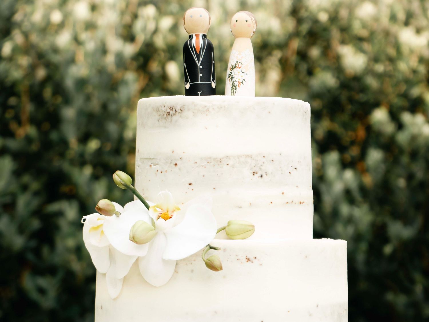 White tiered wedding cake decorated with flowers and a bride and groom topper