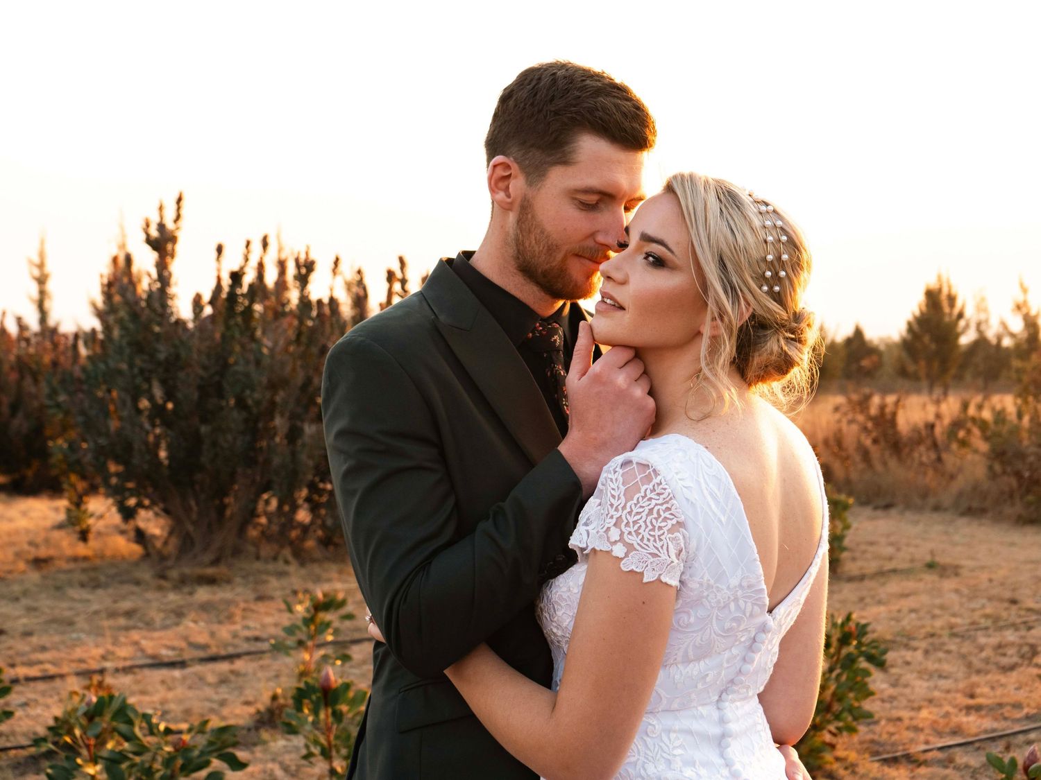 Bride and groom walking hand in hand down a garden path at sunset