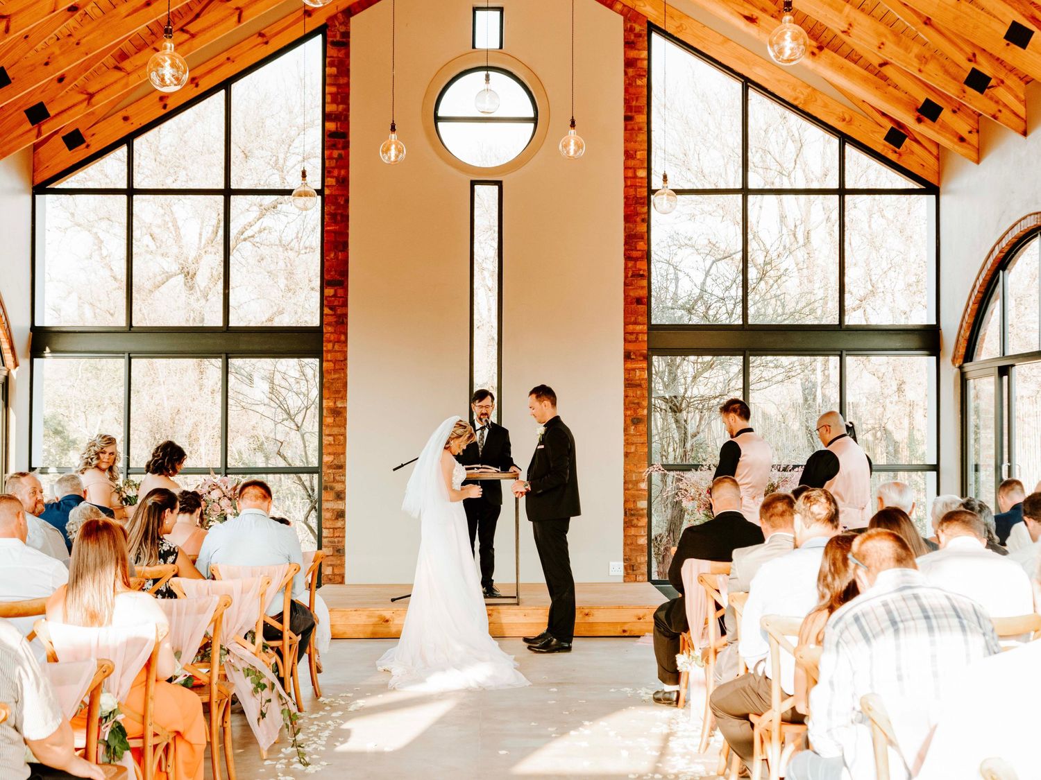 Wedding ceremony inside a timber-beamed barn venue with guests seated