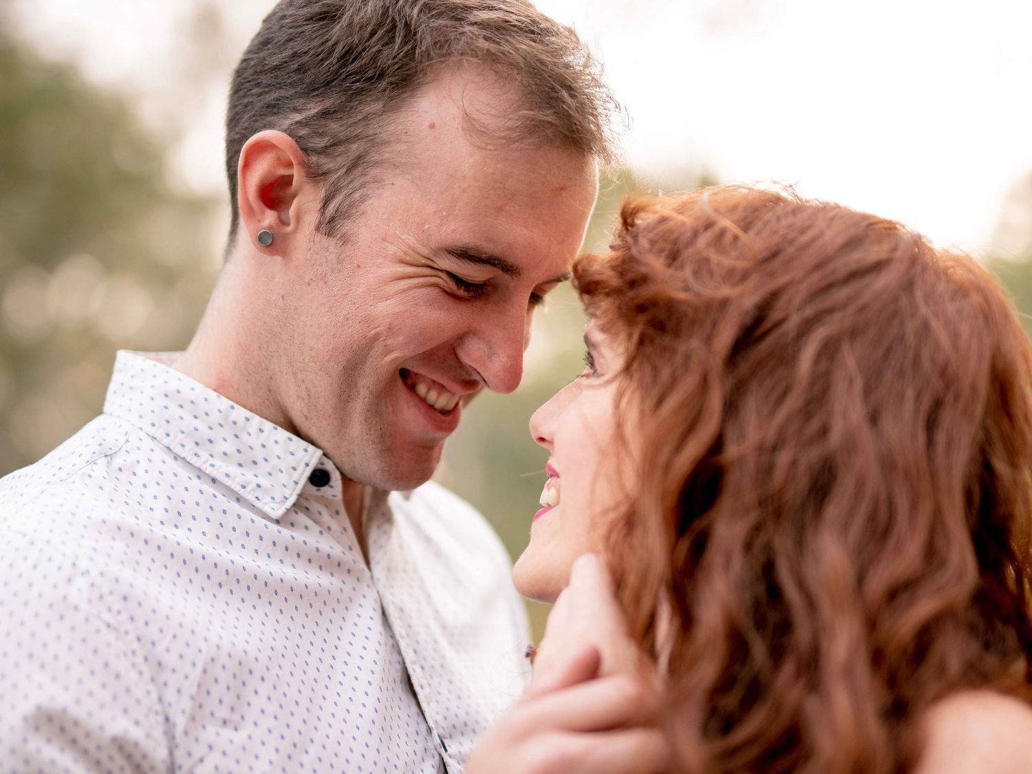 Woman embracing her partner from behind, both smiling, during an engagement shoot