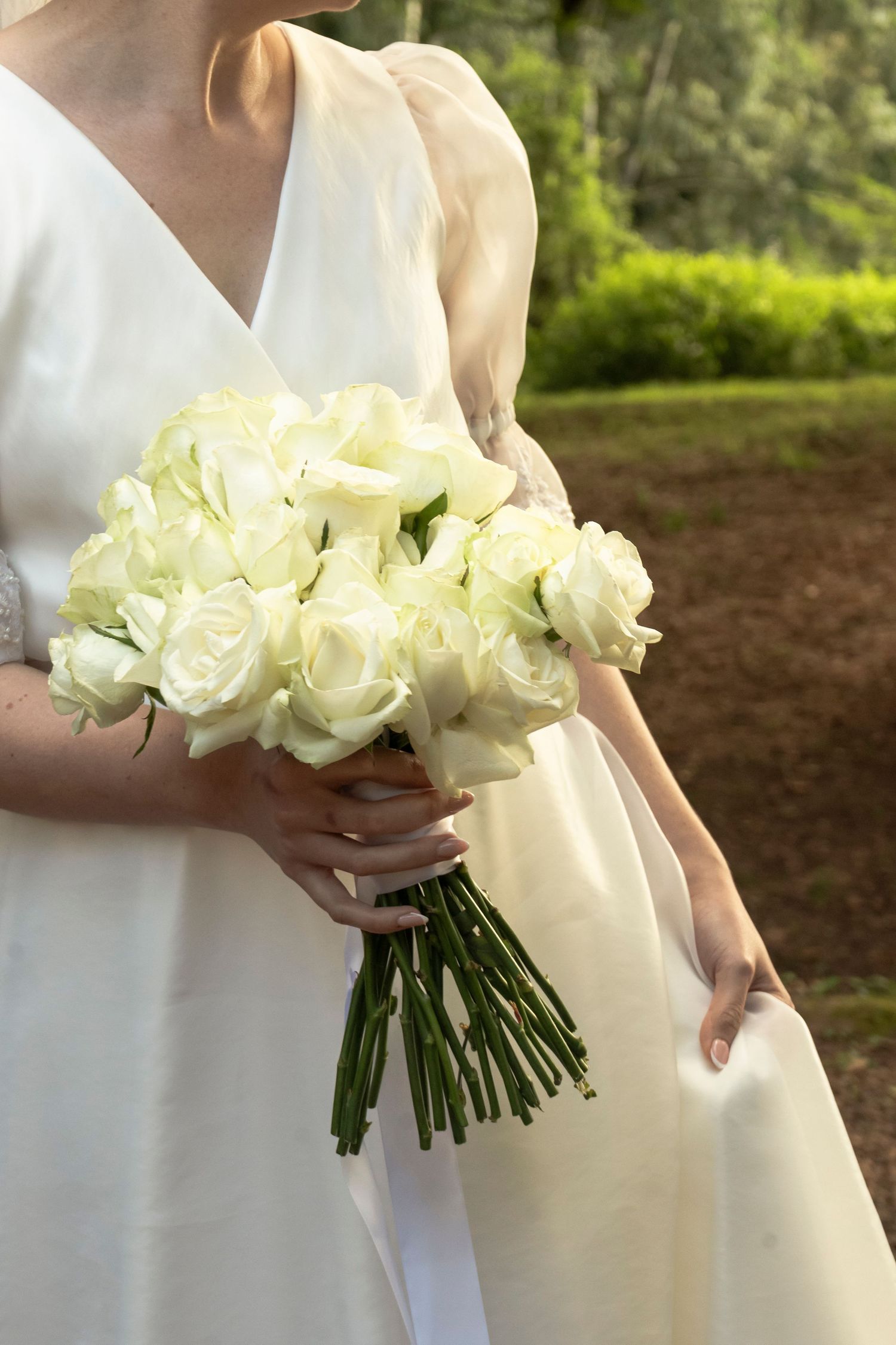 Bride holding a bouquet of white flowers outdoors before the ceremony